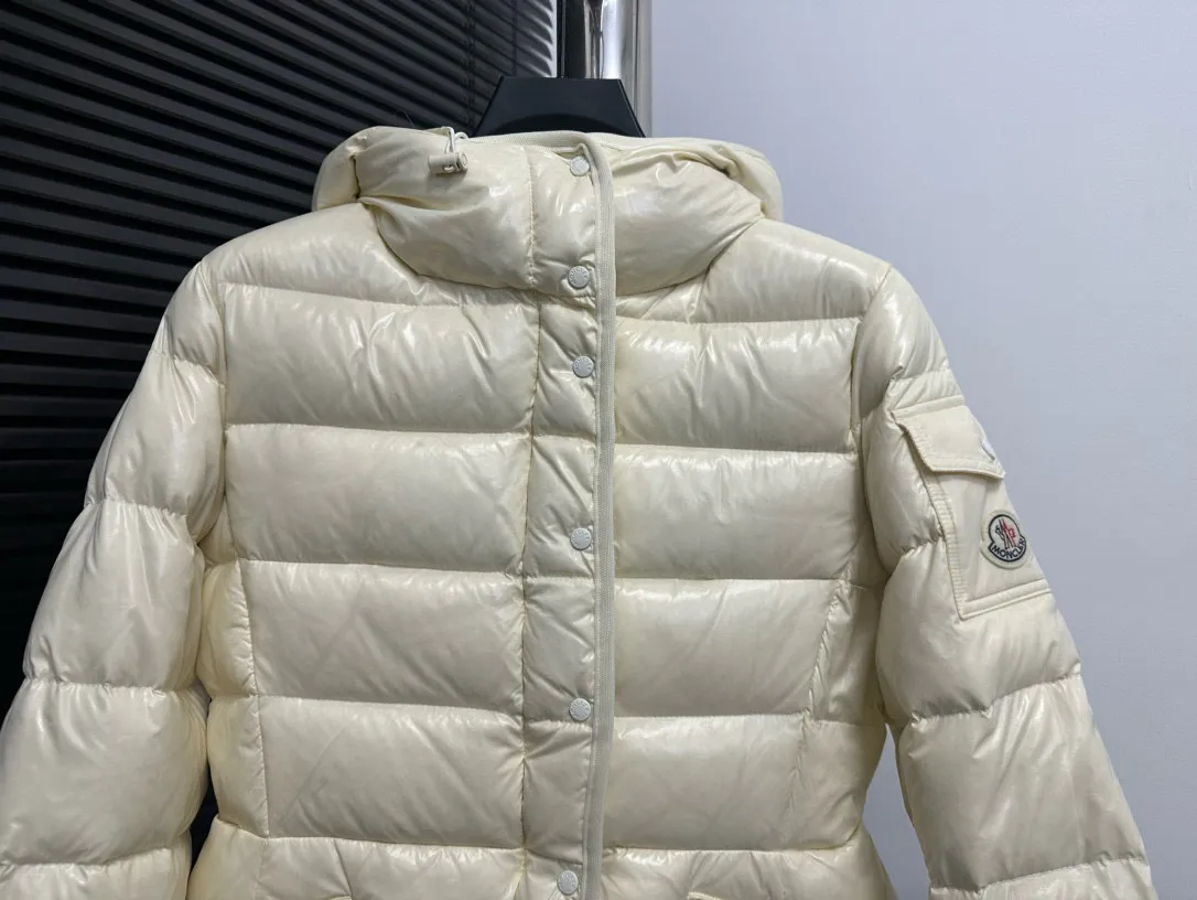 P860 [Moncler] Hooded, waisted women's short down jacket. The barante down jacket is made of glossy nylon fabric and is inspired by the 1970s. It adopts a waist design and presents an A-line silhouette, highlighting a feminine style. An adjustable hood and signature logo patch add finishing touches. Details · Made of lon laqué fabric · lon laqué lining · Filled with down · Adjustable hood · Zipper and snap closure · Suit pocket · Adjustable cuffs Size: 0/1/2/3