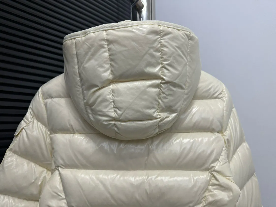 P860 [Moncler] Hooded, waisted women's short down jacket. The barante down jacket is made of glossy nylon fabric and is inspired by the 1970s. It adopts a waist design and presents an A-line silhouette, highlighting a feminine style. An adjustable hood and signature logo patch add finishing touches. Details · Made of lon laqué fabric · lon laqué lining · Filled with down · Adjustable hood · Zipper and snap closure · Suit pocket · Adjustable cuffs Size: 0/1/2/3