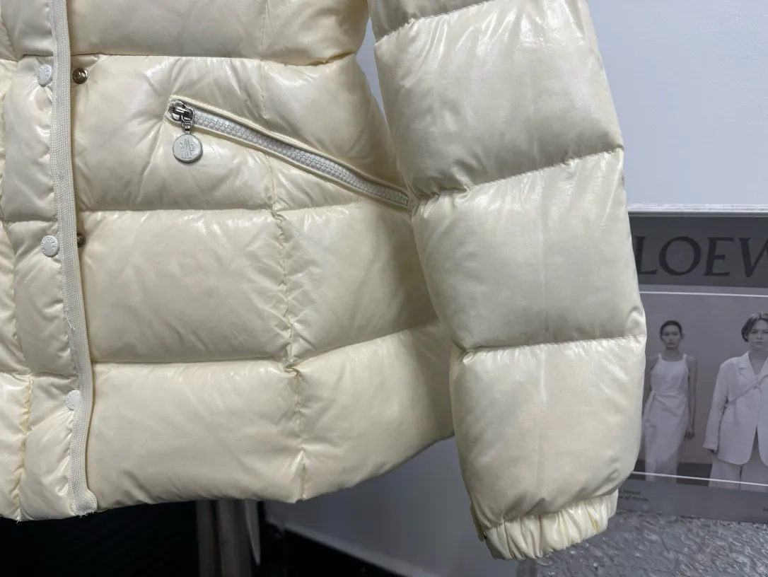 P860 [Moncler] Hooded, waisted women's short down jacket. The barante down jacket is made of glossy nylon fabric and is inspired by the 1970s. It adopts a waist design and presents an A-line silhouette, highlighting a feminine style. An adjustable hood and signature logo patch add finishing touches. Details · Made of lon laqué fabric · lon laqué lining · Filled with down · Adjustable hood · Zipper and snap closure · Suit pocket · Adjustable cuffs Size: 0/1/2/3
