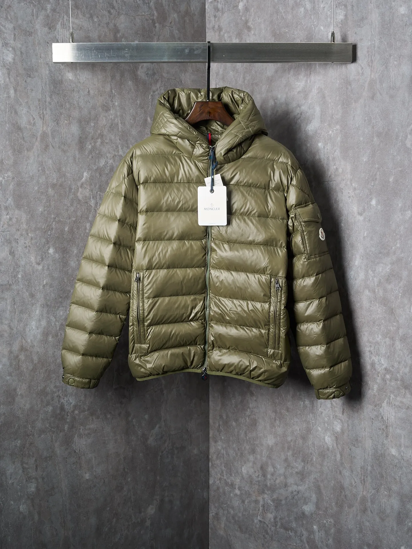 P900 Actual hanging auction] MONCLER/Maskled brim quilted embroidered pocket logo hooded down jacket [Ready stock] 1 2 3 4 Filled with 90 selected white duck down, weighing 210g, ensuring fast fluffy rebound, lightness and warmth.  The longue saison fabric made of high-count polyamide fiber is famous for its excellent tensile strength and lightness. Its good flexibility makes the fabric less prone to wrinkles and keeps it crisp and stylish for a long time. The tight weave effectively blocks the invasion of cold wind and locks in the warm air generated by the down layer. The high-density nylon surface forms a certain lotus leaf effect, making it difficult for small water droplets to penetrate, keeping the interior dry and effectively extending the service life of the down.  The high-density lining is woven with ultra-fine denier, with a thickness of 0.08mm to avoid increasing the overall weight and making it smooth to wear. The high-density woven structure forms a wind resistance layer to protect the thermal efficiency of the thermal layer from loss. It can also withstand the expansion pressure of down and prevent deformation and damage after long-term use.  The quilted letter logo on the brim uses contour quilting technology. The stitches are routed along the edge of the set outline, and the filler is compressed inside the letter graphic, so that the logo is three-dimensional and the pattern is clear.