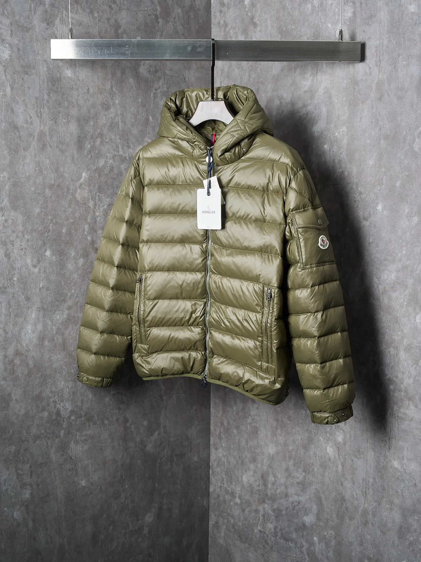 P900 Actual hanging auction] MONCLER/Maskled brim quilted embroidered pocket logo hooded down jacket [Ready stock] 1 2 3 4 Filled with 90 selected white duck down, weighing 210g, ensuring fast fluffy rebound, lightness and warmth.  The longue saison fabric made of high-count polyamide fiber is famous for its excellent tensile strength and lightness. Its good flexibility makes the fabric less prone to wrinkles and keeps it crisp and stylish for a long time. The tight weave effectively blocks the invasion of cold wind and locks in the warm air generated by the down layer. The high-density nylon surface forms a certain lotus leaf effect, making it difficult for small water droplets to penetrate, keeping the interior dry and effectively extending the service life of the down.  The high-density lining is woven with ultra-fine denier, with a thickness of 0.08mm to avoid increasing the overall weight and making it smooth to wear. The high-density woven structure forms a wind resistance layer to protect the thermal efficiency of the thermal layer from loss. It can also withstand the expansion pressure of down and prevent deformation and damage after long-term use.  The quilted letter logo on the brim uses contour quilting technology. The stitches are routed along the edge of the set outline, and the filler is compressed inside the letter graphic, so that the logo is three-dimensional and the pattern is clear.