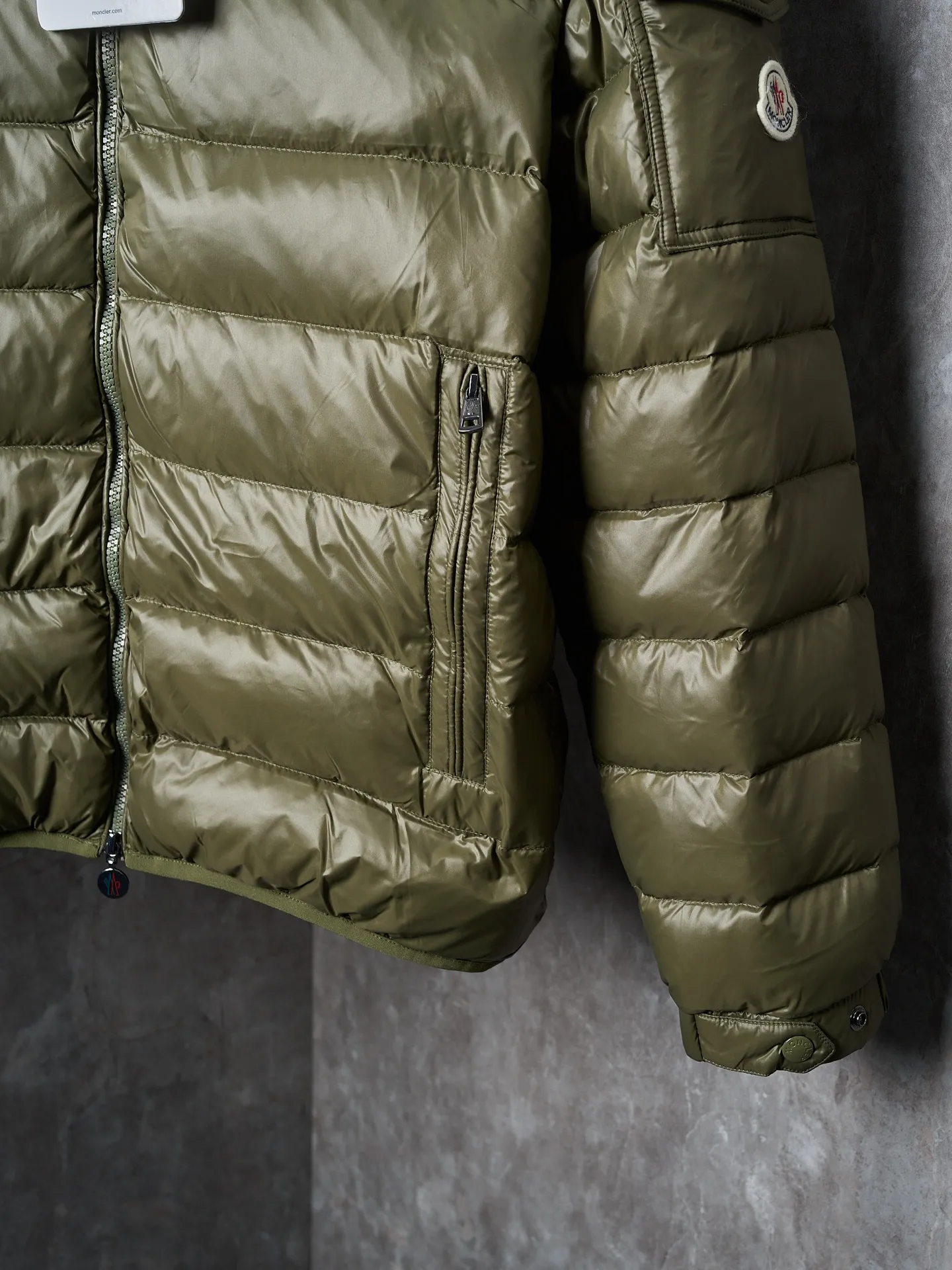 P900 Actual hanging auction] MONCLER/Maskled brim quilted embroidered pocket logo hooded down jacket [Ready stock] 1 2 3 4 Filled with 90 selected white duck down, weighing 210g, ensuring fast fluffy rebound, lightness and warmth.  The longue saison fabric made of high-count polyamide fiber is famous for its excellent tensile strength and lightness. Its good flexibility makes the fabric less prone to wrinkles and keeps it crisp and stylish for a long time. The tight weave effectively blocks the invasion of cold wind and locks in the warm air generated by the down layer. The high-density nylon surface forms a certain lotus leaf effect, making it difficult for small water droplets to penetrate, keeping the interior dry and effectively extending the service life of the down.  The high-density lining is woven with ultra-fine denier, with a thickness of 0.08mm to avoid increasing the overall weight and making it smooth to wear. The high-density woven structure forms a wind resistance layer to protect the thermal efficiency of the thermal layer from loss. It can also withstand the expansion pressure of down and prevent deformation and damage after long-term use.  The quilted letter logo on the brim uses contour quilting technology. The stitches are routed along the edge of the set outline, and the filler is compressed inside the letter graphic, so that the logo is three-dimensional and the pattern is clear.