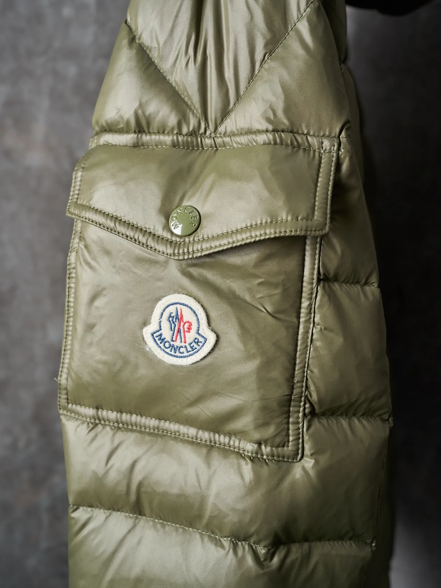 P900 Actual hanging auction] MONCLER/Maskled brim quilted embroidered pocket logo hooded down jacket [Ready stock] 1 2 3 4 Filled with 90 selected white duck down, weighing 210g, ensuring fast fluffy rebound, lightness and warmth.  The longue saison fabric made of high-count polyamide fiber is famous for its excellent tensile strength and lightness. Its good flexibility makes the fabric less prone to wrinkles and keeps it crisp and stylish for a long time. The tight weave effectively blocks the invasion of cold wind and locks in the warm air generated by the down layer. The high-density nylon surface forms a certain lotus leaf effect, making it difficult for small water droplets to penetrate, keeping the interior dry and effectively extending the service life of the down.  The high-density lining is woven with ultra-fine denier, with a thickness of 0.08mm to avoid increasing the overall weight and making it smooth to wear. The high-density woven structure forms a wind resistance layer to protect the thermal efficiency of the thermal layer from loss. It can also withstand the expansion pressure of down and prevent deformation and damage after long-term use.  The quilted letter logo on the brim uses contour quilting technology. The stitches are routed along the edge of the set outline, and the filler is compressed inside the letter graphic, so that the logo is three-dimensional and the pattern is clear.