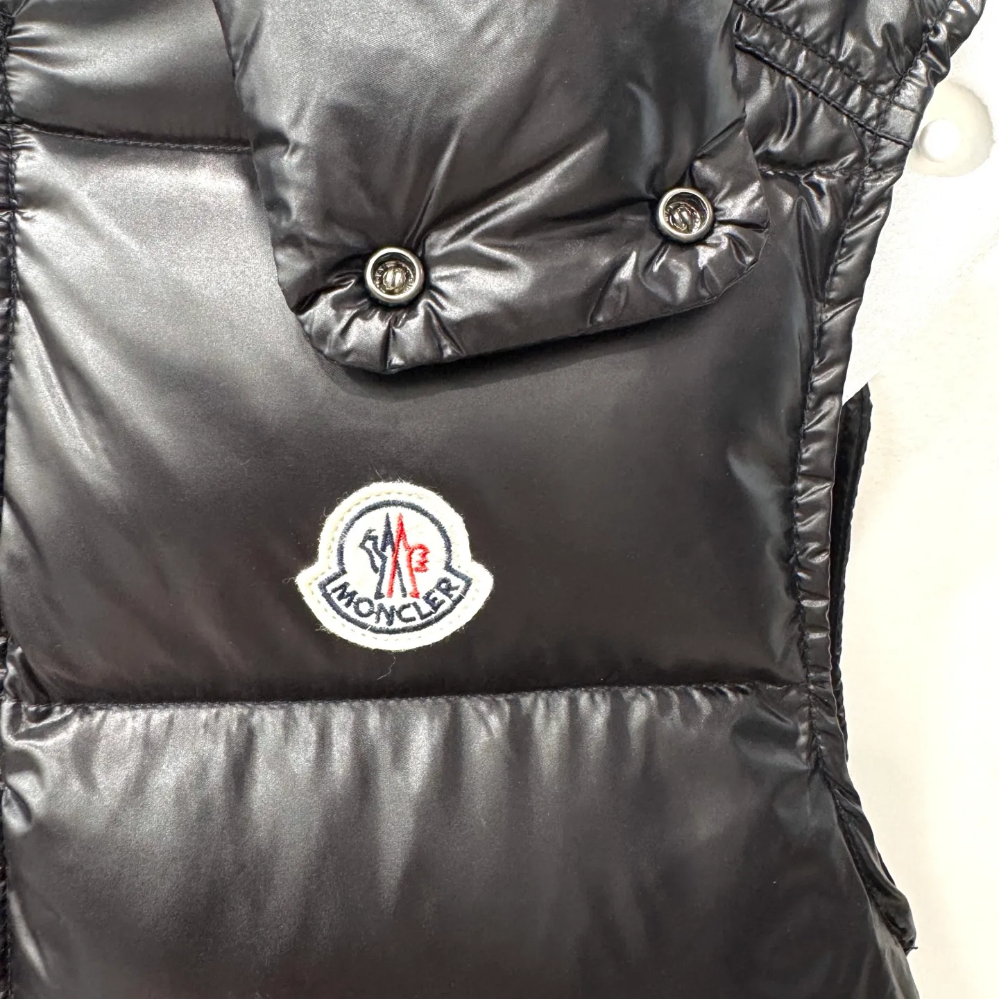 P580 Bormes Men's Hooded Down Vest] The Bormes men's vest is classic and timeless, with colors and details reminiscent of the Paninari trend of the 1980s.    The Bormes down vest is made from signature glossy nylon laqué fabric with classic checkered quilting for excellent warmth and protection. Two-way zipper closure design, with Moncler logo-shaped zipper puller.  • Made of nylon laqué • Nylon laqué lining • Filled with down • Detachable and adjustable hood • Collar with press buttons • Zipper closure • Zippered pockets • Fabric: 100% nylon; • Lining: 100% nylon; • Filling: Goose down • Down content: 90%; excluding upholstery; • Size: 12345 Maximum wash temperature 30°C - Gentle wash; Do not bleach; Do not tumble dry; Iron maximum temperature 110°C - without steam; Do not dry clean; Professional wet cleaning - gentle wash; Lay flat to dry in shade; Wash separately; Recommend washing and ironing inside out