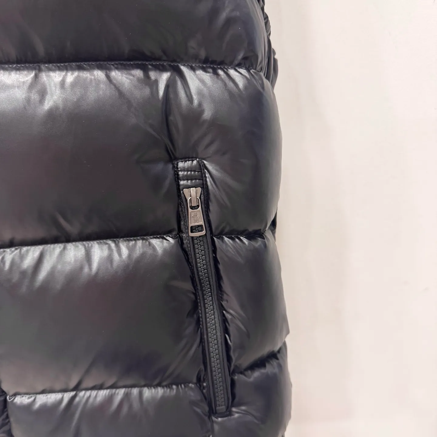 P580 Bormes Men's Hooded Down Vest] The Bormes men's vest is classic and timeless, with colors and details reminiscent of the Paninari trend of the 1980s.    The Bormes down vest is made from signature glossy nylon laqué fabric with classic checkered quilting for excellent warmth and protection. Two-way zipper closure design, with Moncler logo-shaped zipper puller.  • Made of nylon laqué • Nylon laqué lining • Filled with down • Detachable and adjustable hood • Collar with press buttons • Zipper closure • Zippered pockets • Fabric: 100% nylon; • Lining: 100% nylon; • Filling: Goose down • Down content: 90%; excluding upholstery; • Size: 12345 Maximum wash temperature 30°C - Gentle wash; Do not bleach; Do not tumble dry; Iron maximum temperature 110°C - without steam; Do not dry clean; Professional wet cleaning - gentle wash; Lay flat to dry in shade; Wash separately; Recommend washing and ironing inside out
