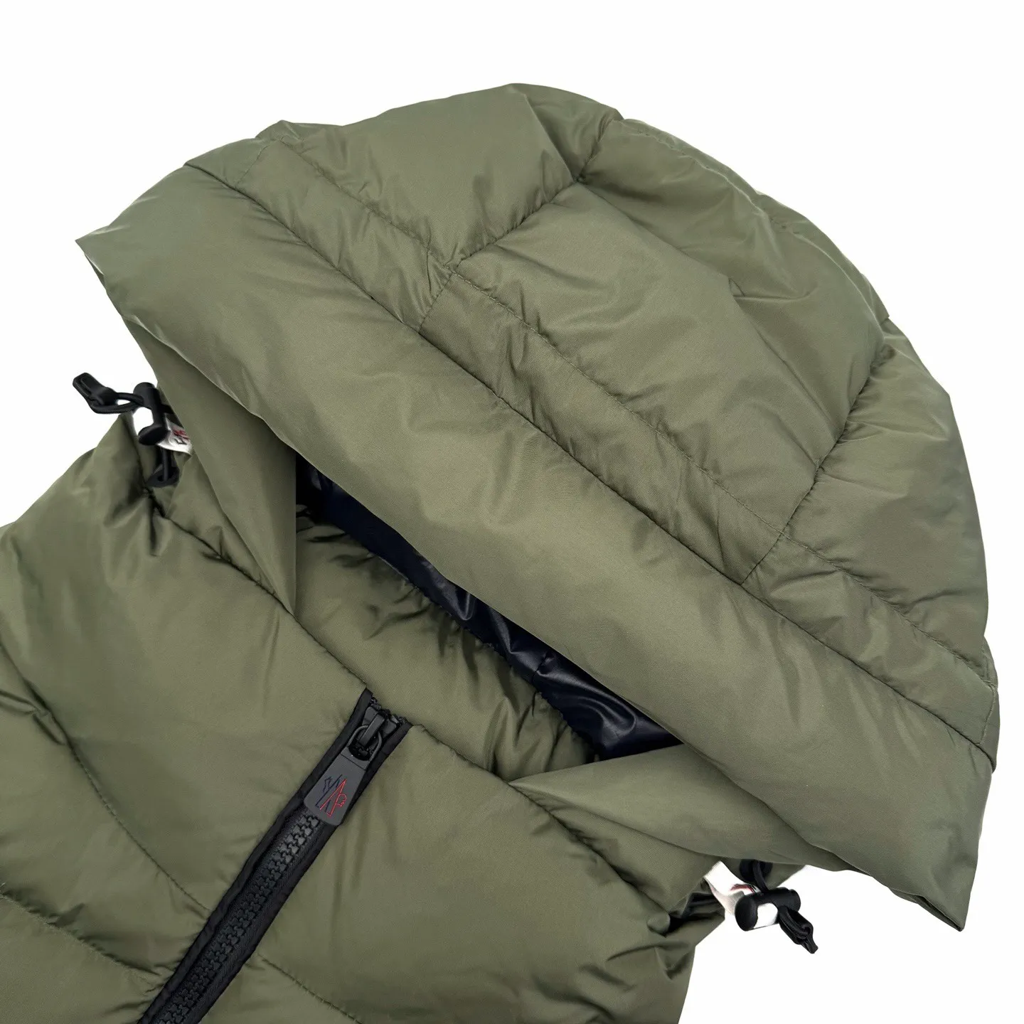 P780 Moncler logo woven splicing down jacket (green). The fabric is made of customized matte lattice air shield velvet and 300D high-density calendered coating. It uses the new national standard 90 white duck down (welcome to test). It has a full amount of down and is warm. It is light and fluffy. It uses the dark green of the overlapping mountains as the background. Everything is accumulating. It creates its own scenery in silence. The Monlcer triangle logo is embellished on the chest. The power aesthetic of the minimalist logo. The concentrated down filling in the front panel creates dynamic insulation for the core heat dissipation zone of the human body. The hooded down is a moving warm flow barrier for the head and neck, forming a thermal energy circulation system with the front panel. The elastic woven sleeves provide freedom of movement with a sense of compression, forming a relaxed and warm philosophy. The real high-end is to let function become the footnote of style, and computer mechanical down filling is given priority by making liner paper patterns to determine the down filling area according to the original three-dimensional effect. Determine the gram weight of down per square meter according to the original three-dimensional effect, thereby calculating the filling amount of each piece. The computer down filling machine uses a digital weighing unit to achieve stable measurement and 3D three-dimensional quilting technology. With the help of the CNC quilting machine's programming system, the down in different areas is accurately separated to ensure that the filling is evenly fixed after sewing. To avoid agglomeration or shifting, the computer template machine runs the line. The computer template machine's line process shows extremely high neatness and smoothness. The craftsman accurately controls the size during the operation to ensure that each row line meets the design requirements. The lines of the entire template are smooth and uniform. Neat and beautiful, the triple overlocking and five-thread dense stitching process uses main seam overlocking + diagonal reinforcement + raw edge wrapping. The triple structure forms a three-dimensional protective net at the edge of the fabric to avoid stitch breakage. Size:S-M-L-XL