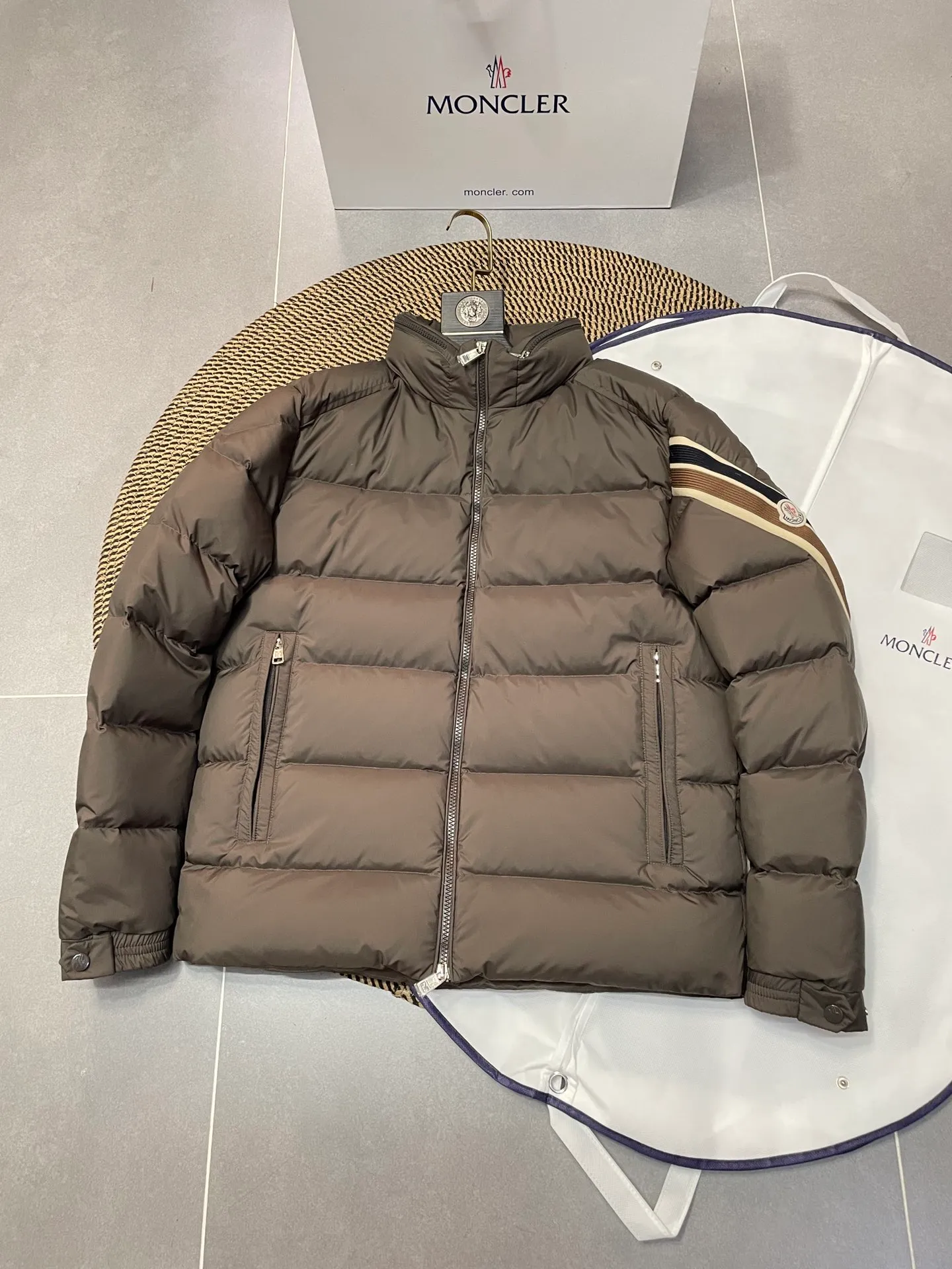 P840 🆕❤️2️⃣0️⃣2️⃣4️⃣🆕Premium down⬆️Moncler Solayan men's three-color trim short down jacket. Premium goose down filling. The finest, lightest and neatest fabric. Solayan men's short down jacket is decorated with seasonal iconic stripe details, blending sportsmanship and timeless style.  The Solayan down jacket is made of micro chic fabric and has a tough square shape design, highlighting Moncler's sporty spirit. This cropped down jacket features tricolor stripes on the sleeves, a seasonal take on the brand's signature. Comes with a practical pull-out hood. Details •Made from micro chic nylon fabric •Micro chic nylon lining •Down filled •Pull-out hood •Zip closure •Zip pockets •Adjustable cuffs •Elastic drawstring hem •Tri-color trim on sleeves Size: 1-5 Color: White Dark Brown Black