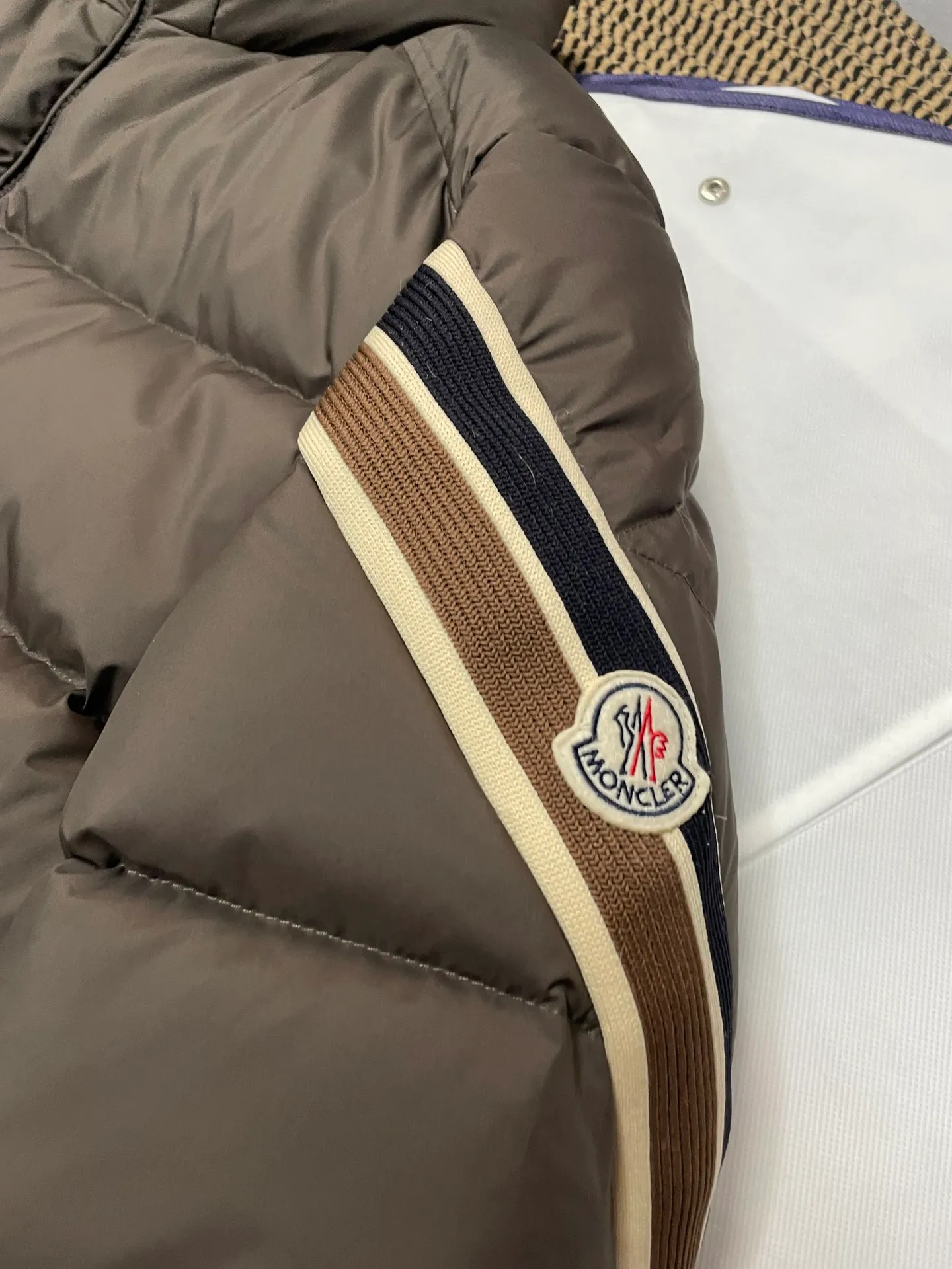 P840 🆕❤️2️⃣0️⃣2️⃣4️⃣🆕Premium down⬆️Moncler Solayan men's three-color trim short down jacket. Premium goose down filling. The finest, lightest and neatest fabric. Solayan men's short down jacket is decorated with seasonal iconic stripe details, blending sportsmanship and timeless style.  The Solayan down jacket is made of micro chic fabric and has a tough square shape design, highlighting Moncler's sporty spirit. This cropped down jacket features tricolor stripes on the sleeves, a seasonal take on the brand's signature. Comes with a practical pull-out hood. Details •Made from micro chic nylon fabric •Micro chic nylon lining •Down filled •Pull-out hood •Zip closure •Zip pockets •Adjustable cuffs •Elastic drawstring hem •Tri-color trim on sleeves Size: 1-5 Color: White Dark Brown Black