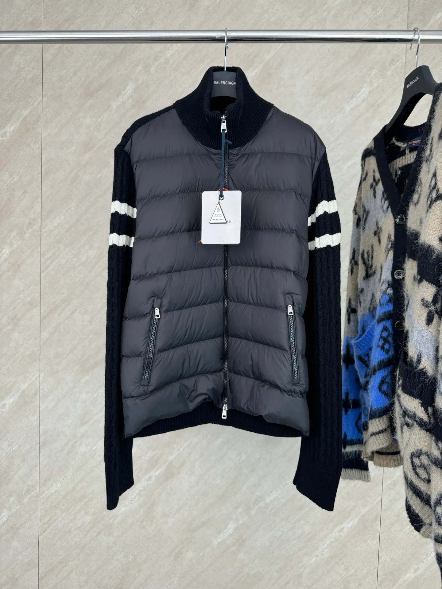 P810 Moncler Mouth Woolen Spliced ​​Down Jacket Size: 1 2 3 4 Fabric Selection: The outer front fabric is made of 100% nylon (nylon). Its high-density structure achieves excellent windproof effect. It also has strong wear resistance and wrinkle resistance. It is not afraid of scratches in daily wear and is easy to take care of.  The splicing design of sweaters and down jackets not only retains the thermal performance of down jackets, but also incorporates the fashion elements of sweaters, making the overall garment both practical and fashionable.  High-quality material: filled with high-quality white duck down, with a filling capacity of 100g, which has excellent thermal insulation effect. At the same time, the sweater is made of wool, cashmere and other natural fibers, which are soft, comfortable and skin-friendly.  The sweaters and down jackets are carefully spliced ​​to ensure comfortable wearing and are not prone to threading or velvet loss.  High collar design: not only provides excellent thermal insulation effect, but also adds a unique sense of fashion, allowing the wearer to maintain style in the cold season.  Stripe decoration: The stripes on the sleeve arms are like bright brush strokes, embellished on the dark gray down jacket, injecting vitality and movement into the overall look, making the clothing more eye-catching.  Accessories: one-to-one customized zipper puller, one-to-one customized armband