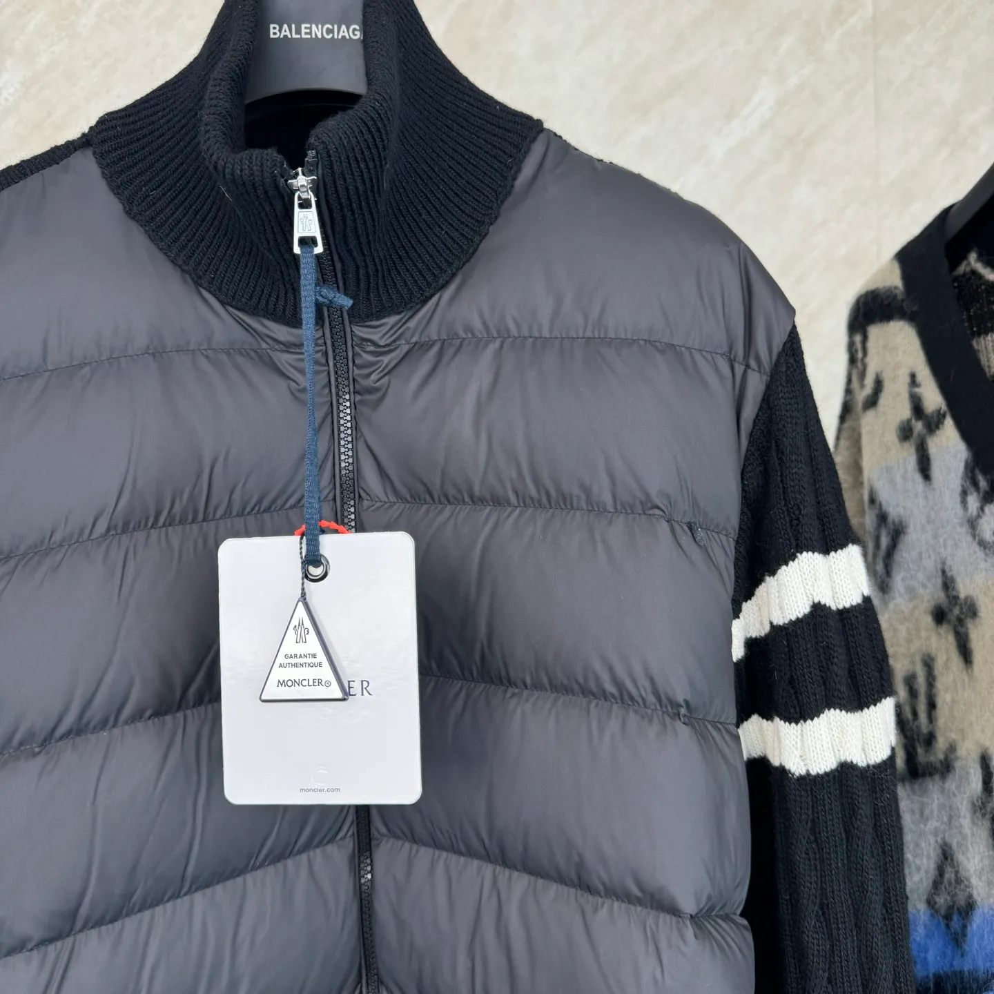 P810 Moncler Mouth Woolen Spliced ​​Down Jacket Size: 1 2 3 4 Fabric Selection: The outer front fabric is made of 100% nylon (nylon). Its high-density structure achieves excellent windproof effect. It also has strong wear resistance and wrinkle resistance. It is not afraid of scratches in daily wear and is easy to take care of.  The splicing design of sweaters and down jackets not only retains the thermal performance of down jackets, but also incorporates the fashion elements of sweaters, making the overall garment both practical and fashionable.  High-quality material: filled with high-quality white duck down, with a filling capacity of 100g, which has excellent thermal insulation effect. At the same time, the sweater is made of wool, cashmere and other natural fibers, which are soft, comfortable and skin-friendly.  The sweaters and down jackets are carefully spliced ​​to ensure comfortable wearing and are not prone to threading or velvet loss.  High collar design: not only provides excellent thermal insulation effect, but also adds a unique sense of fashion, allowing the wearer to maintain style in the cold season.  Stripe decoration: The stripes on the sleeve arms are like bright brush strokes, embellished on the dark gray down jacket, injecting vitality and movement into the overall look, making the clothing more eye-catching.  Accessories: one-to-one customized zipper puller, one-to-one customized armband