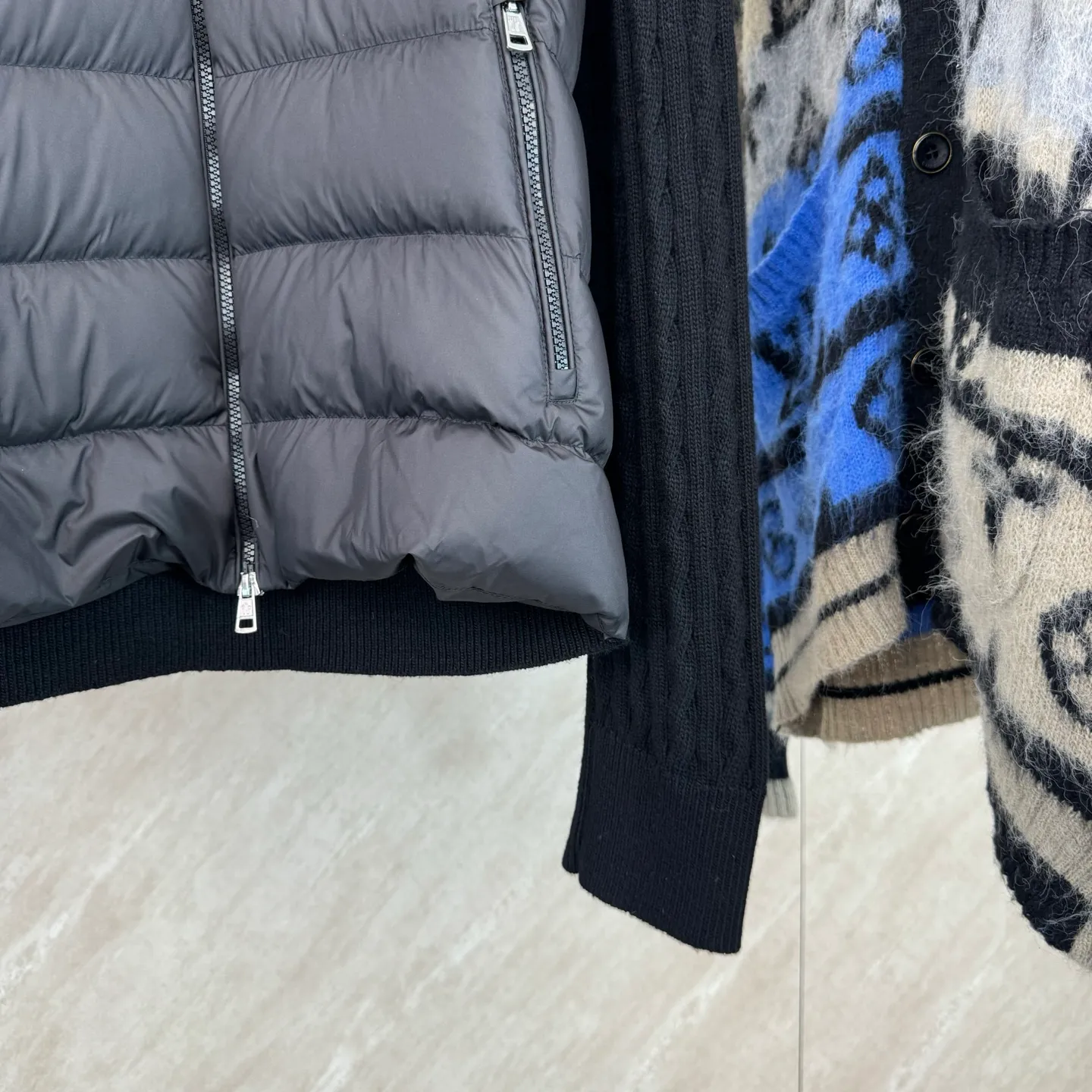 P810 Moncler Mouth Woolen Spliced ​​Down Jacket Size: 1 2 3 4 Fabric Selection: The outer front fabric is made of 100% nylon (nylon). Its high-density structure achieves excellent windproof effect. It also has strong wear resistance and wrinkle resistance. It is not afraid of scratches in daily wear and is easy to take care of.  The splicing design of sweaters and down jackets not only retains the thermal performance of down jackets, but also incorporates the fashion elements of sweaters, making the overall garment both practical and fashionable.  High-quality material: filled with high-quality white duck down, with a filling capacity of 100g, which has excellent thermal insulation effect. At the same time, the sweater is made of wool, cashmere and other natural fibers, which are soft, comfortable and skin-friendly.  The sweaters and down jackets are carefully spliced ​​to ensure comfortable wearing and are not prone to threading or velvet loss.  High collar design: not only provides excellent thermal insulation effect, but also adds a unique sense of fashion, allowing the wearer to maintain style in the cold season.  Stripe decoration: The stripes on the sleeve arms are like bright brush strokes, embellished on the dark gray down jacket, injecting vitality and movement into the overall look, making the clothing more eye-catching.  Accessories: one-to-one customized zipper puller, one-to-one customized armband