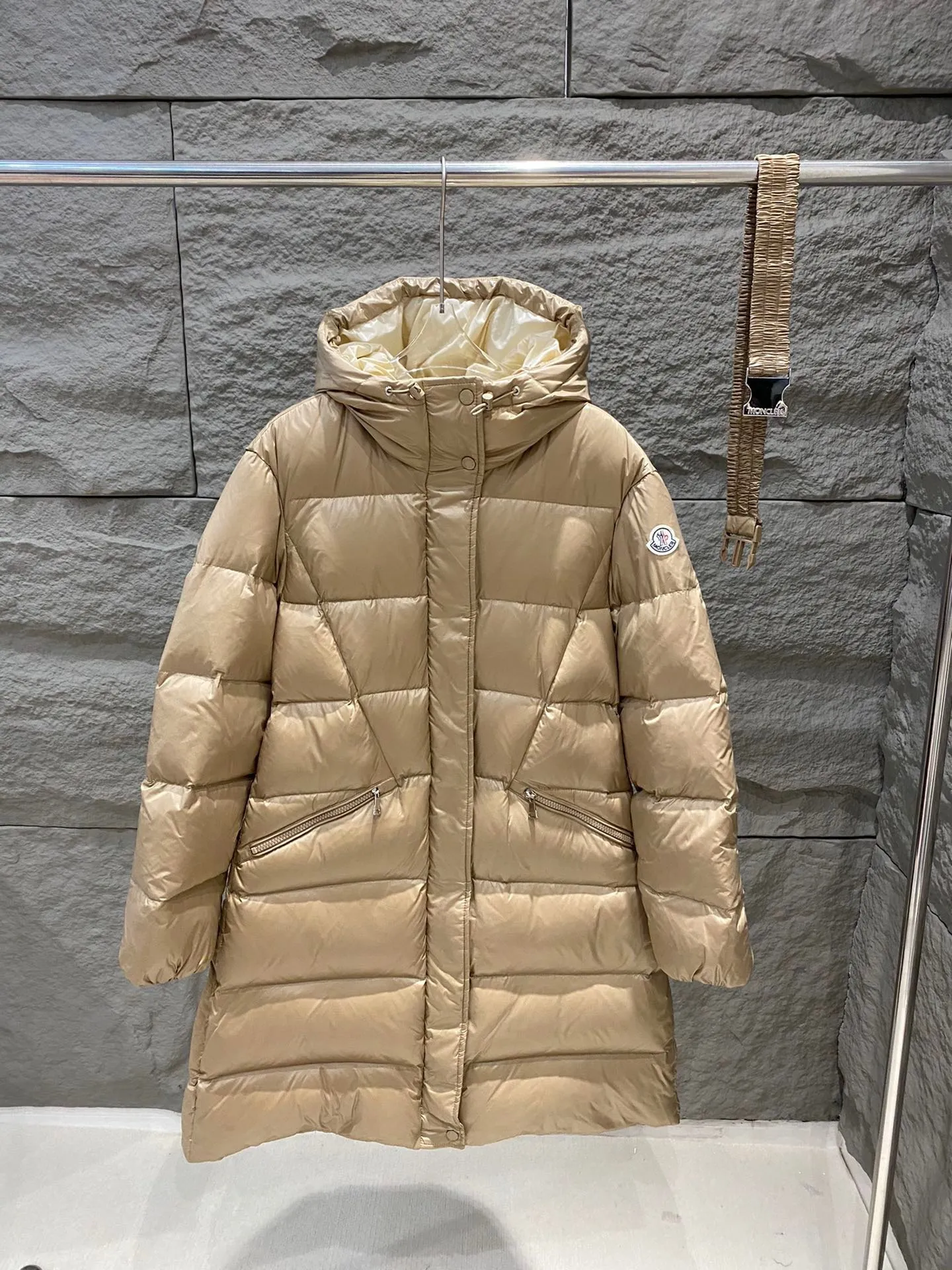 P1180 Moncler Bellevue Women's Long Belted Down Jacket The Bellevue down jacket is made of iconic nylon laqué fabric, interpreting classic Moncler style. Long design, the fabric has been functionally treated for a gorgeous lustrous effect. This hooded thermal piece has a feminine silhouette and an elastic waistband. From day to night, from the city to the mountains, it can be easily handled. Color: black/khaki Size: 0/1/2/3