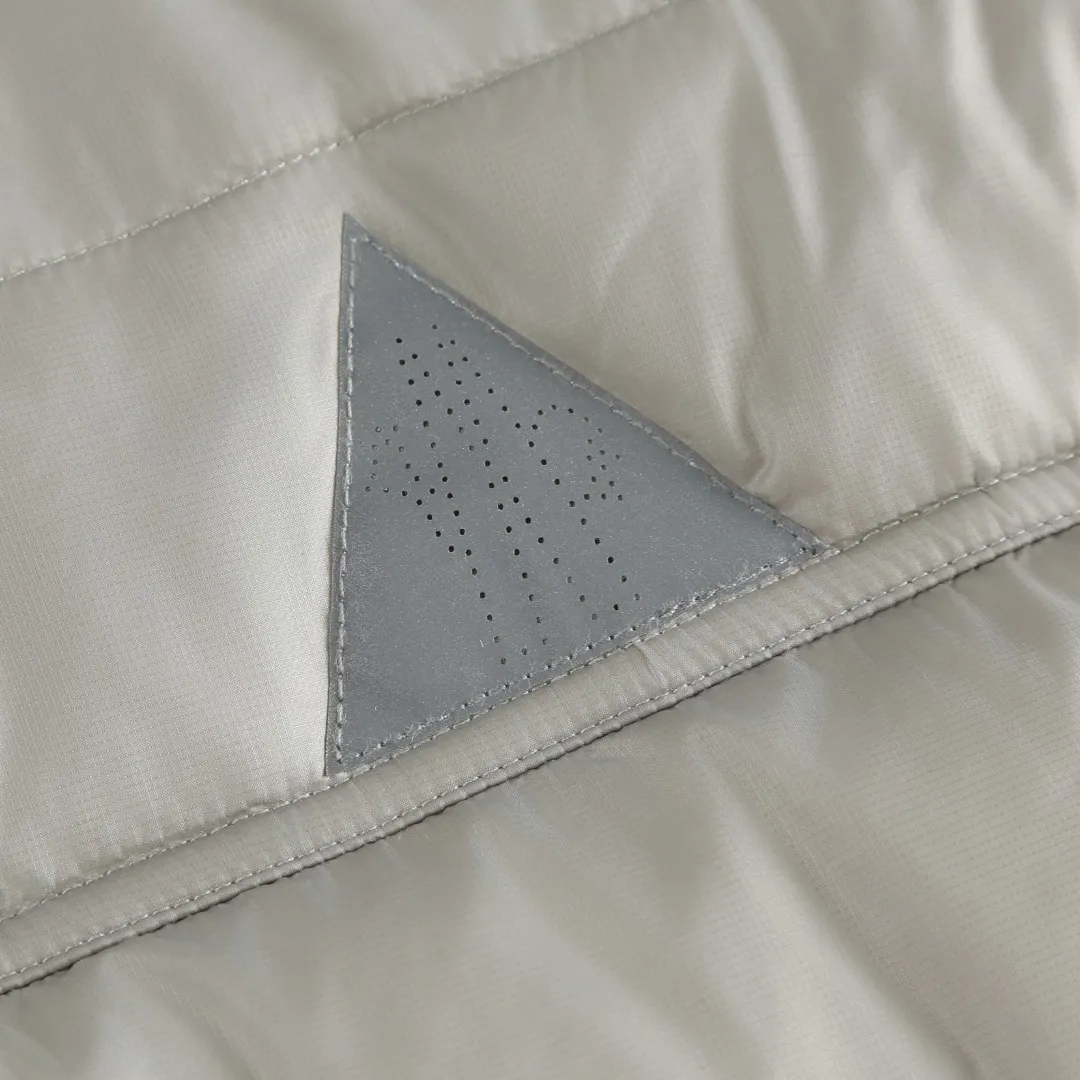 P680 MONCLER down vest with reflective markings Fabric selection: Made of ultra-fine nylon yarn woven in a high-density manner. The number of yarns per unit area is large, and the gaps between the yarns are very small, which can effectively block the penetration of cold wind. The fine weave keeps it lightweight and soft to the touch, physically restricting the lightweight down fibers from slipping through the gaps. Nylon fiber itself has good wear resistance and is not easy to snag, which significantly extends its service life and can easily cope with the needs of multiple scenarios.  Lining selection: The lining is made of 100% polyester fiber high-density weaving. The thickness of 0.08mm avoids increasing the overall weight and makes it smooth to wear. The high-density weaving structure forms a wind resistance layer to protect the thermal efficiency of the thermal insulation layer from loss. At the same time, it can withstand the expansion pressure of down and prevent deformation and damage after long-term use.  High-quality filling: 90 white duck down is selected, with a weight of 130g, ensuring excellent thermal insulation performance. After strict screening and processing, the velvet is not easy to get drilled, ensuring durability.  Process: Through the reflective cloth punching process, the logo is regularly arranged on the triangular reflective mark with dozens of small holes, which not only improves the functionality, but also strengthens the recognition and aesthetics.   Accessories: One-to-one customized snap buttons, one-to-one customized zipper pullers, one-to-one customized badges, one-to-one customized elastic buckles, etc. SIZE: 1 2 3 4