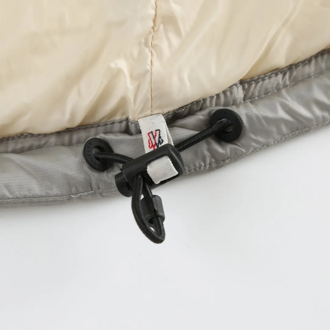 P680 MONCLER down vest with reflective markings Fabric selection: Made of ultra-fine nylon yarn woven in a high-density manner. The number of yarns per unit area is large, and the gaps between the yarns are very small, which can effectively block the penetration of cold wind. The fine weave keeps it lightweight and soft to the touch, physically restricting the lightweight down fibers from slipping through the gaps. Nylon fiber itself has good wear resistance and is not easy to snag, which significantly extends its service life and can easily cope with the needs of multiple scenarios.  Lining selection: The lining is made of 100% polyester fiber high-density weaving. The thickness of 0.08mm avoids increasing the overall weight and makes it smooth to wear. The high-density weaving structure forms a wind resistance layer to protect the thermal efficiency of the thermal insulation layer from loss. At the same time, it can withstand the expansion pressure of down and prevent deformation and damage after long-term use.  High-quality filling: 90 white duck down is selected, with a weight of 130g, ensuring excellent thermal insulation performance. After strict screening and processing, the velvet is not easy to get drilled, ensuring durability.  Process: Through the reflective cloth punching process, the logo is regularly arranged on the triangular reflective mark with dozens of small holes, which not only improves the functionality, but also strengthens the recognition and aesthetics.   Accessories: One-to-one customized snap buttons, one-to-one customized zipper pullers, one-to-one customized badges, one-to-one customized elastic buckles, etc. SIZE: 1 2 3 4