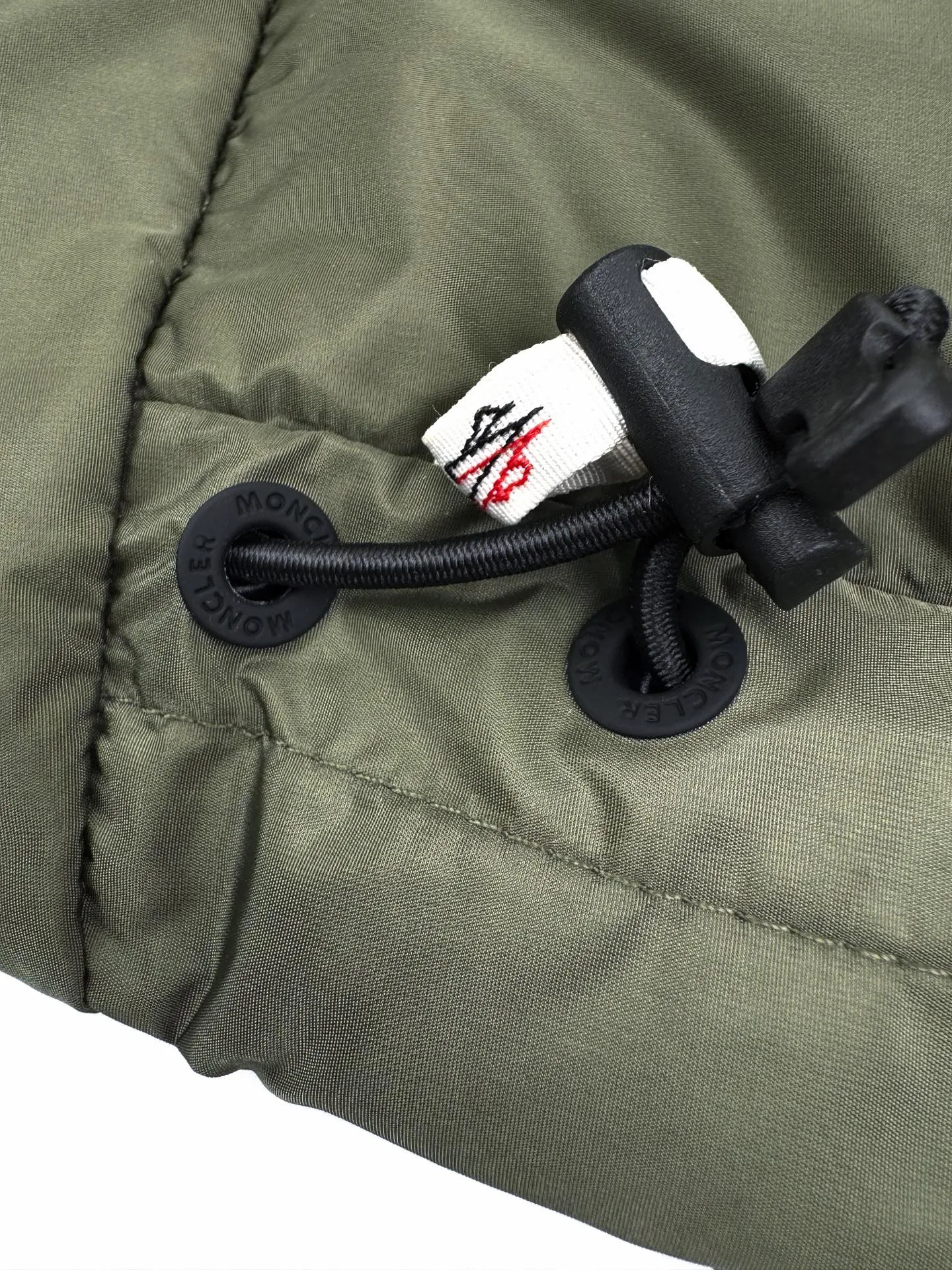 P780 Moncler logo woven splicing down jacket, custom-made matte lattice air shield down and 300D high-density calendered coating, using the new national standard 90 white duck down (welcome to test), full of down, full of warmth, light and fluffy, with the dark green of the overlapping mountains as the background, all things accumulating, creating its own scenery in silence The Monlcer triangle logo is embellished on the chest, the power aesthetics of the minimalist logo The concentrated down filling in the front area creates dynamic insulation for the core heat dissipation zone of the human body. The hooded down is a moving warm flow barrier for the head and neck, forming a thermal energy circulation system with the front area. The elastic woven sleeves provide freedom of movement with a sense of compression, forming a relaxed and warm philosophy. The real high-end is to let function become the footnote of style. Process 1: Computer mechanical down filling. Prioritize the liner pattern by making a pattern to determine the down filling area and determine the weight of down per square meter according to the original three-dimensional effect. Thus, the amount of down filling for each cut piece is calculated. The computer down filling machine uses a digital weighing unit to achieve stable measurement. Process 2: 3D three-dimensional quilting technology. With the programming system of the CNC quilting machine, the down in different areas is accurately separated to ensure that the filling is evenly fixed after sewing and avoid agglomeration or displacement. Process 3: Computer template machine line running process. The computer template machine line line process shows extremely high neatness and smoothness. The craftsman's precise control of the size during the operation ensures that each line meets the design requirements. The lines of the entire template are smooth and unified, neat and beautiful. Process 4: Triple locking five-thread dense stitching process. Main seam locking + diagonal reinforcement + raw edge wrapping. Triple structure to form a three-dimensional protective net at the edge of the fabric to avoid stitch breakage. Paving materials: Customized 1:1 Moncler zipper. Customized 1:1 Moncler rope loop. Customized 1:1 Moncler logo. Customized 1:1 Moncler. Corns Customized 1:1 Moncler trademark Size: S M L XL Style number: 25378