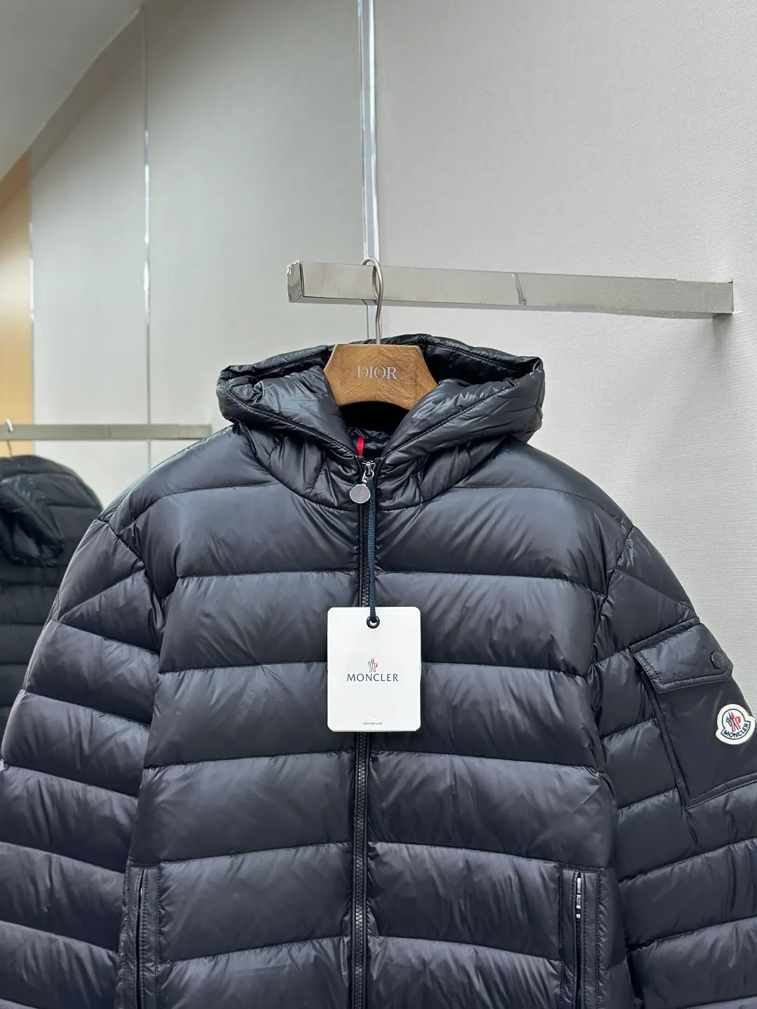 P910 MONCLER hooded brim quilted embroidered down jacket Fabric selection: The longue saison fabric is made of high-count polyamide fiber, which is known for its excellent tensile strength and lightness. Its good flexibility makes the fabric less prone to wrinkles and keeps it crisp and stylish for a long time. The tight weave effectively blocks the invasion of cold wind and locks in the warm air generated by the down layer. The high-density nylon surface forms a certain lotus leaf effect, making it difficult for small water droplets to penetrate, keeping the interior dry and effectively extending the service life of the down.  Lining selection: High-density lining fabric made of ultra-fine denier, 0.08mm thickness to avoid increasing the overall weight and making it smooth to wear. The high-density woven structure forms a wind resistance layer to protect the thermal efficiency of the thermal layer from loss. It can also withstand the expansion pressure of down and prevent deformation and damage after long-term use.  Technology: The quilted letter logo on the brim uses contour quilting technology. The stitching is routed along the edge of the set outline, and the filler is compressed inside the letter graphic, so that the logo is three-dimensional and convex, and the pattern is clear.  High-quality filling: It is filled with 90% selected white duck down, weighing 210g, ensuring fluffy rebound, lightness and warmth.  Accessories: customized zipper pendant, customized badge, customized three-label SIZE: 1 2 3 4