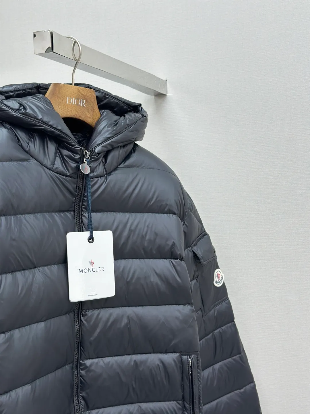 P910 MONCLER hooded brim quilted embroidered down jacket Fabric selection: The longue saison fabric is made of high-count polyamide fiber, which is known for its excellent tensile strength and lightness. Its good flexibility makes the fabric less prone to wrinkles and keeps it crisp and stylish for a long time. The tight weave effectively blocks the invasion of cold wind and locks in the warm air generated by the down layer. The high-density nylon surface forms a certain lotus leaf effect, making it difficult for small water droplets to penetrate, keeping the interior dry and effectively extending the service life of the down.  Lining selection: High-density lining fabric made of ultra-fine denier, 0.08mm thickness to avoid increasing the overall weight and making it smooth to wear. The high-density woven structure forms a wind resistance layer to protect the thermal efficiency of the thermal layer from loss. It can also withstand the expansion pressure of down and prevent deformation and damage after long-term use.  Technology: The quilted letter logo on the brim uses contour quilting technology. The stitching is routed along the edge of the set outline, and the filler is compressed inside the letter graphic, so that the logo is three-dimensional and convex, and the pattern is clear.  High-quality filling: It is filled with 90% selected white duck down, weighing 210g, ensuring fluffy rebound, lightness and warmth.  Accessories: customized zipper pendant, customized badge, customized three-label SIZE: 1 2 3 4