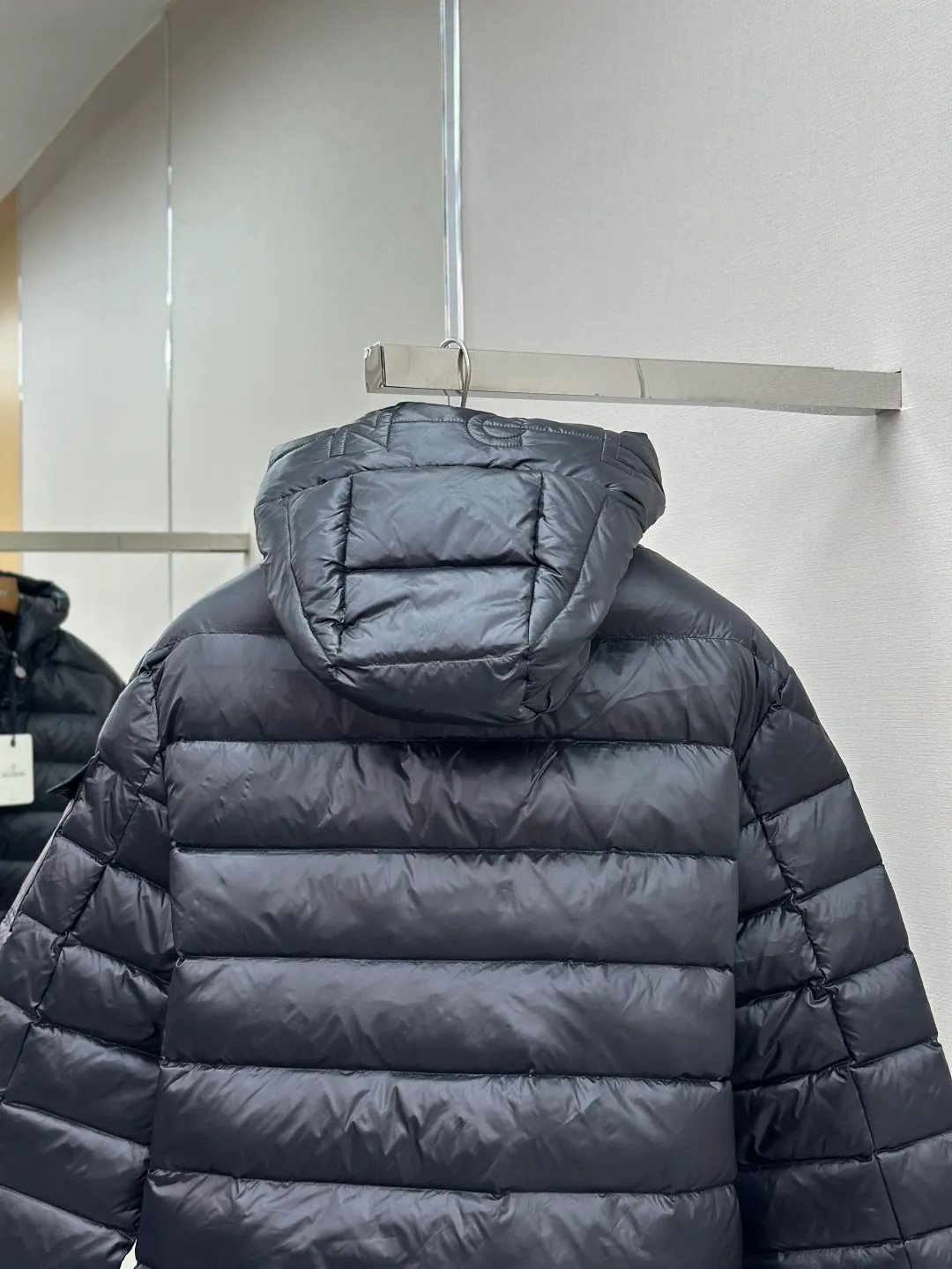 P910 MONCLER hooded brim quilted embroidered down jacket Fabric selection: The longue saison fabric is made of high-count polyamide fiber, which is known for its excellent tensile strength and lightness. Its good flexibility makes the fabric less prone to wrinkles and keeps it crisp and stylish for a long time. The tight weave effectively blocks the invasion of cold wind and locks in the warm air generated by the down layer. The high-density nylon surface forms a certain lotus leaf effect, making it difficult for small water droplets to penetrate, keeping the interior dry and effectively extending the service life of the down.  Lining selection: High-density lining fabric made of ultra-fine denier, 0.08mm thickness to avoid increasing the overall weight and making it smooth to wear. The high-density woven structure forms a wind resistance layer to protect the thermal efficiency of the thermal layer from loss. It can also withstand the expansion pressure of down and prevent deformation and damage after long-term use.  Technology: The quilted letter logo on the brim uses contour quilting technology. The stitching is routed along the edge of the set outline, and the filler is compressed inside the letter graphic, so that the logo is three-dimensional and convex, and the pattern is clear.  High-quality filling: It is filled with 90% selected white duck down, weighing 210g, ensuring fluffy rebound, lightness and warmth.  Accessories: customized zipper pendant, customized badge, customized three-label SIZE: 1 2 3 4