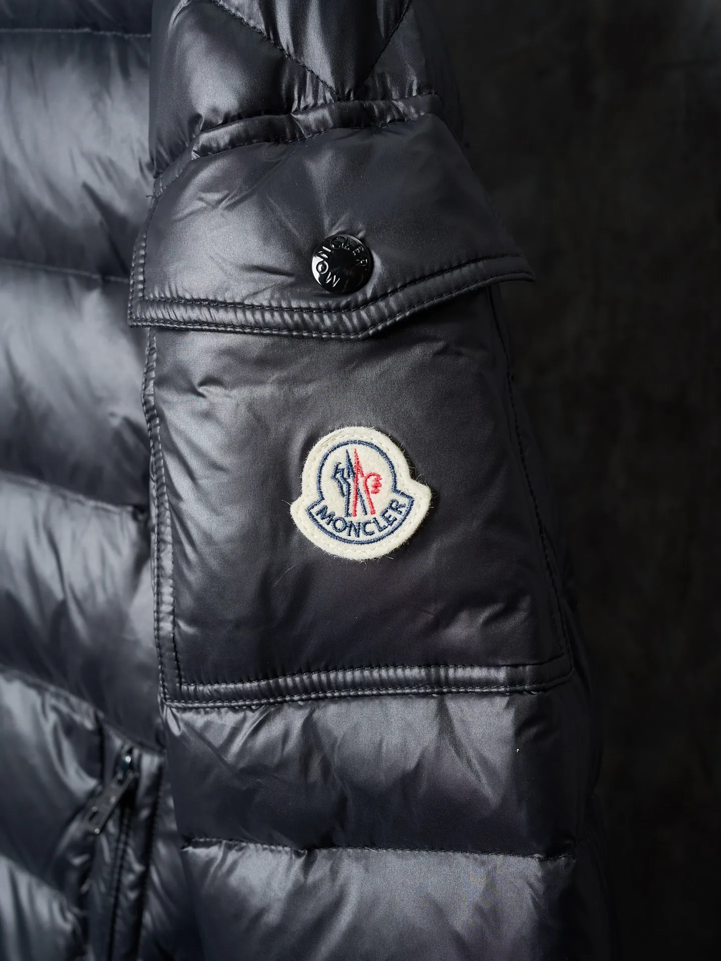 P900 Actual hanging auction] MONCLER/Maskled brim quilted embroidered pocket logo hooded down jacket [Ready stock] 1 2 3 4 Filled with 90 selected white duck down, weighing 210g, ensuring fast fluffy rebound, lightness and warmth.  The longue saison fabric made of high-count polyamide fiber is famous for its excellent tensile strength and lightness. Its good flexibility makes the fabric less prone to wrinkles and keeps it crisp and stylish for a long time. The tight weave effectively blocks the invasion of cold wind and locks in the warm air generated by the down layer. The high-density nylon surface forms a certain lotus leaf effect, making it difficult for small water droplets to penetrate, keeping the interior dry and effectively extending the service life of the down.  The high-density lining is woven with ultra-fine denier, with a thickness of 0.08mm to avoid increasing the overall weight and making it smooth to wear. The high-density woven structure forms a wind resistance layer to protect the thermal efficiency of the thermal layer from loss. It can also withstand the expansion pressure of down and prevent deformation and damage after long-term use.  The quilted letter logo on the brim uses contour quilting technology. The stitches are routed along the edge of the set outline, and the filler is compressed inside the letter graphic, so that the logo is three-dimensional and the pattern is clear.