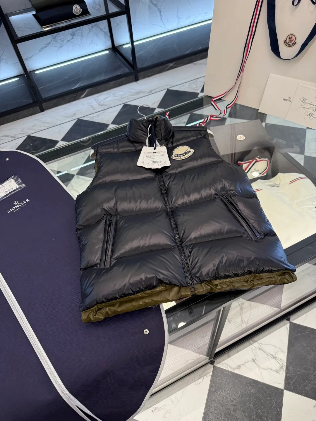 P660 Moncler Lipsi down vest. Contrast color splicing design. Super full filling. Lipsi men's down vest is made of shiny nylon laqué fabric, suitable for wearing in different seasons, bringing warmth and care.  The Lipsi short down vest embodies Moncler's classic design and is a must-have item for your wardrobe from season to season. Crafted from lightweight, functional nylon laqué fabric, it has a contrast lining for a vibrant feel. Details •Made from lightweight nylon laqué fabric •Lightweight nylon laqué lining •Filled with down •Stand-up collar •Zipper closure •Zip pockets •Chenille logo patch Size: 1-5 Black/Ivory Couple Style
