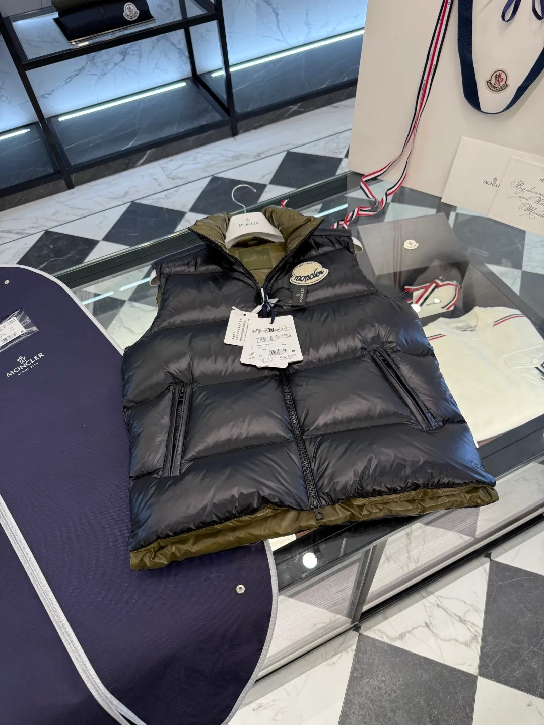 P660 Moncler Lipsi down vest. Contrast color splicing design. Super full filling. Lipsi men's down vest is made of shiny nylon laqué fabric, suitable for wearing in different seasons, bringing warmth and care.  The Lipsi short down vest embodies Moncler's classic design and is a must-have item for your wardrobe from season to season. Crafted from lightweight, functional nylon laqué fabric, it has a contrast lining for a vibrant feel. Details •Made from lightweight nylon laqué fabric •Lightweight nylon laqué lining •Filled with down •Stand-up collar •Zipper closure •Zip pockets •Chenille logo patch Size: 1-5 Black/Ivory Couple Style