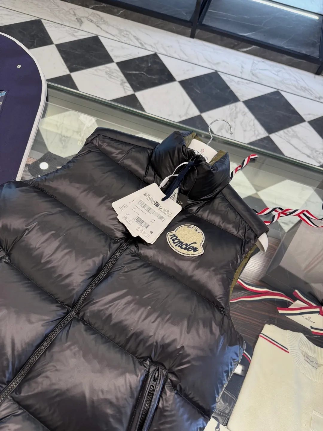 P660 Moncler Lipsi down vest. Contrast color splicing design. Super full filling. Lipsi men's down vest is made of shiny nylon laqué fabric, suitable for wearing in different seasons, bringing warmth and care.  The Lipsi short down vest embodies Moncler's classic design and is a must-have item for your wardrobe from season to season. Crafted from lightweight, functional nylon laqué fabric, it has a contrast lining for a vibrant feel. Details •Made from lightweight nylon laqué fabric •Lightweight nylon laqué lining •Filled with down •Stand-up collar •Zipper closure •Zip pockets •Chenille logo patch Size: 1-5 Black/Ivory Couple Style