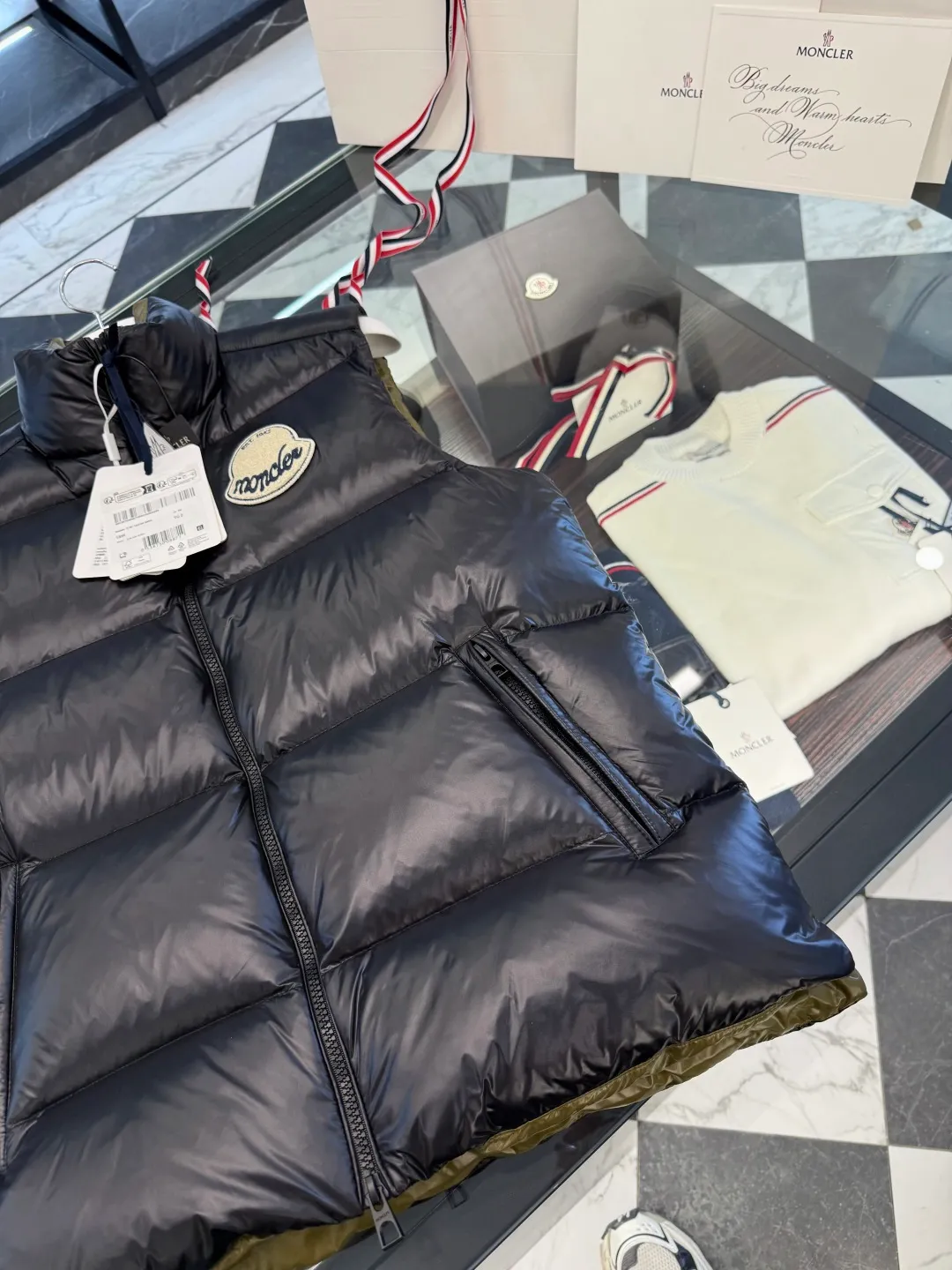 P660 Moncler Lipsi down vest. Contrast color splicing design. Super full filling. Lipsi men's down vest is made of shiny nylon laqué fabric, suitable for wearing in different seasons, bringing warmth and care.  The Lipsi short down vest embodies Moncler's classic design and is a must-have item for your wardrobe from season to season. Crafted from lightweight, functional nylon laqué fabric, it has a contrast lining for a vibrant feel. Details •Made from lightweight nylon laqué fabric •Lightweight nylon laqué lining •Filled with down •Stand-up collar •Zipper closure •Zip pockets •Chenille logo patch Size: 1-5 Black/Ivory Couple Style
