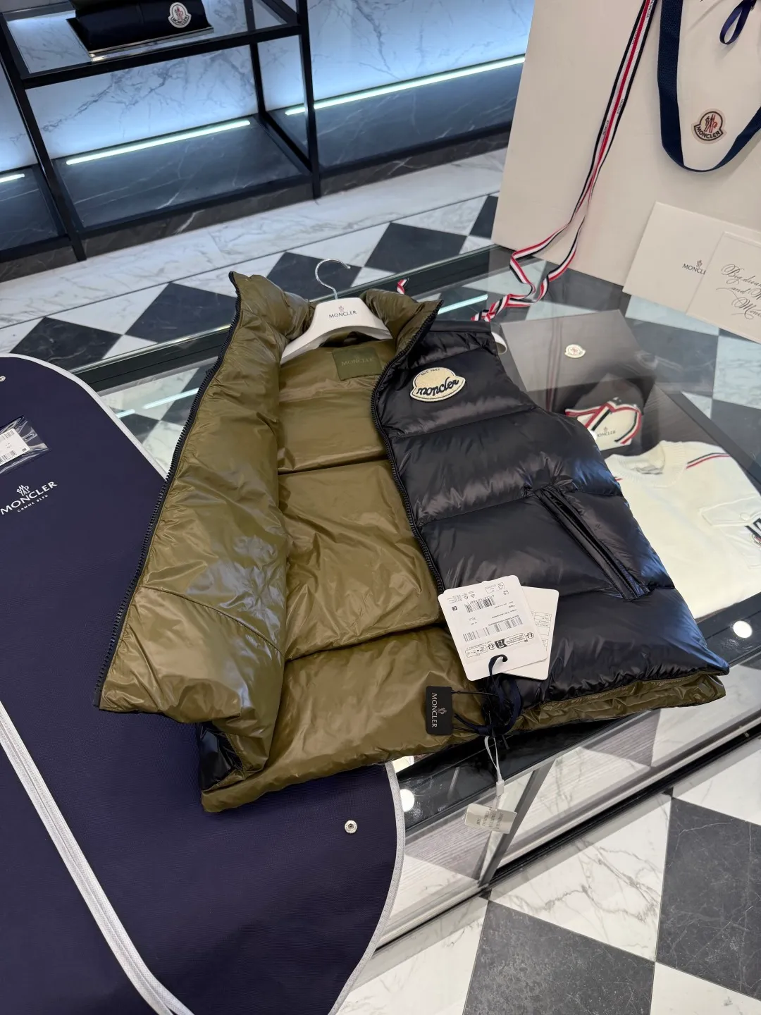 P660 Moncler Lipsi down vest. Contrast color splicing design. Super full filling. Lipsi men's down vest is made of shiny nylon laqué fabric, suitable for wearing in different seasons, bringing warmth and care.  The Lipsi short down vest embodies Moncler's classic design and is a must-have item for your wardrobe from season to season. Crafted from lightweight, functional nylon laqué fabric, it has a contrast lining for a vibrant feel. Details •Made from lightweight nylon laqué fabric •Lightweight nylon laqué lining •Filled with down •Stand-up collar •Zipper closure •Zip pockets •Chenille logo patch Size: 1-5 Black/Ivory Couple Style