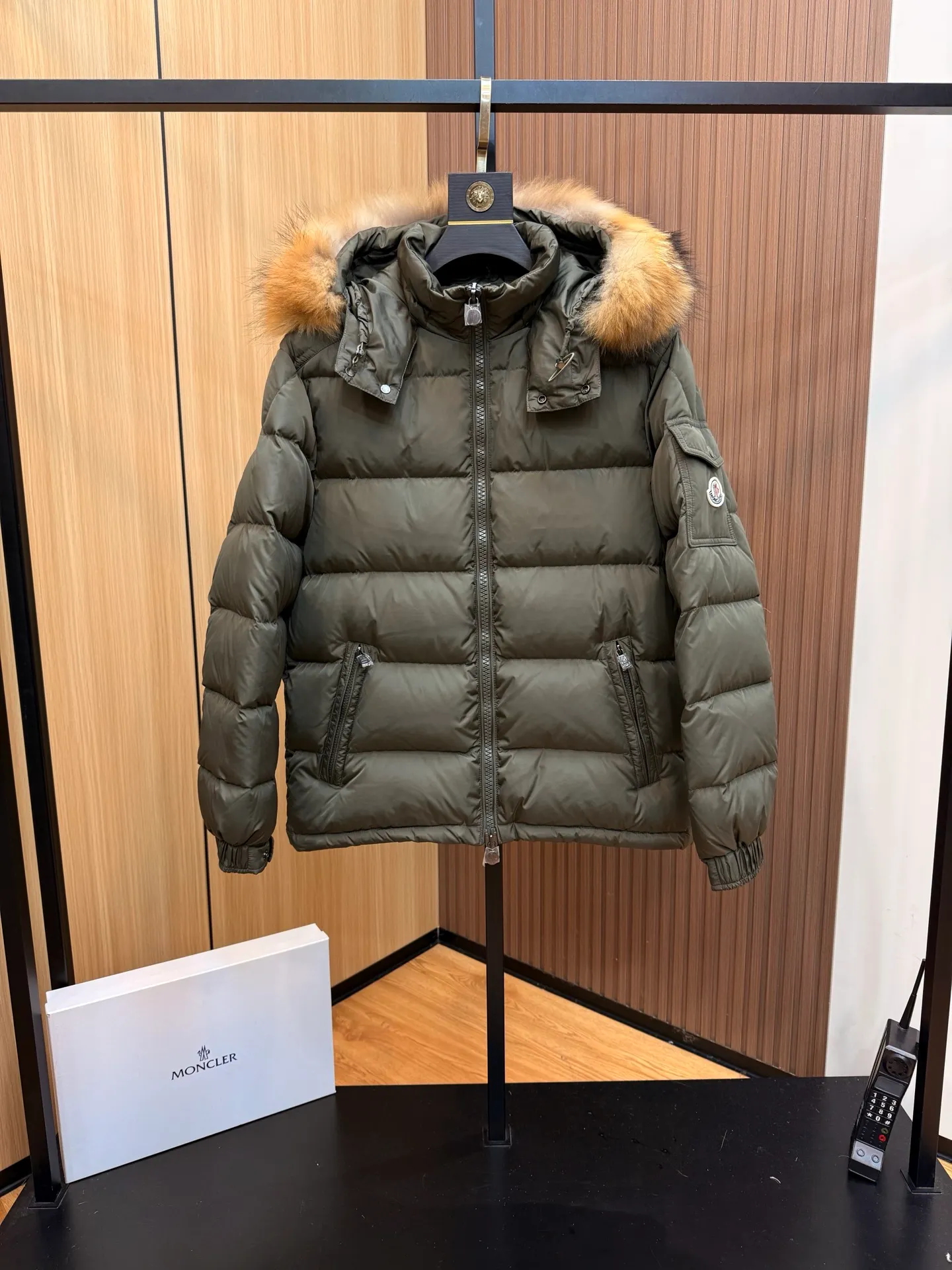 P1040 Moncler Mayaf short men's down jacket. The hood is removable. The fur collar is removable. Based on Maya, a removable fur collar is added. The Mayaf men's hooded down jacket is made of functional nylon fabric, and the hood is equipped with removable synthetic material trim.  The Mayaf short down jacket is a reinterpretation of the classic Moncler Maya style in an instantly recognizable silhouette, with a removable hood and adjustable hem. Made from functional fabric with removable synthetic trim on the hood. The sleeves are embellished with classic patch pockets, reflecting the brand's signature style. Details •Made from functional fabric •Technical fabric lining •Down-filled •Push-stud collar •Detachable hood with removable synthetic trim •Zip closure •Zip pockets •Patch pockets with press-stud •Adjustable elastic cuffs •Adjustable drawstring hem