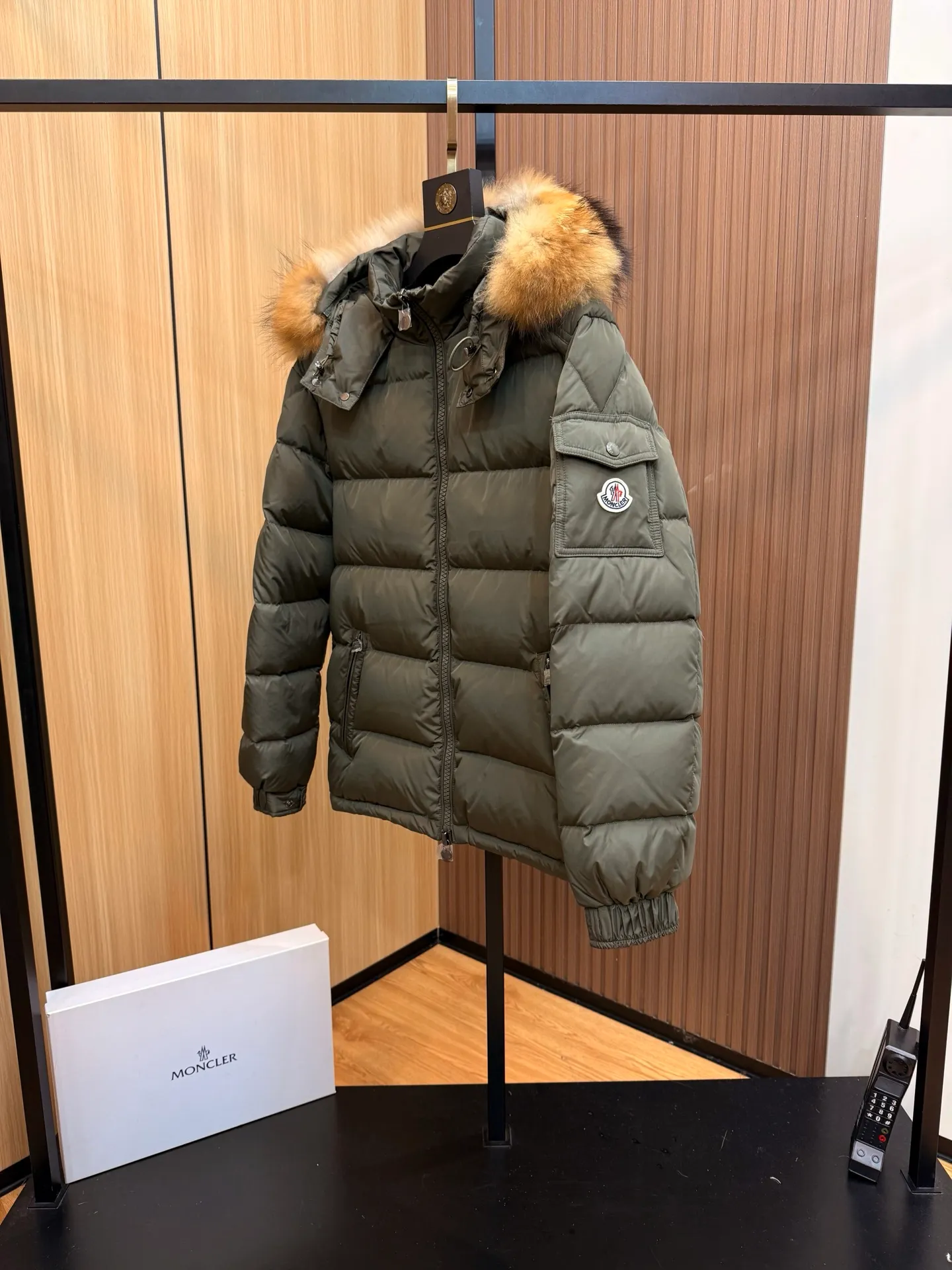 P1040 Moncler Mayaf short men's down jacket. The hood is removable. The fur collar is removable. Based on Maya, a removable fur collar is added. The Mayaf men's hooded down jacket is made of functional nylon fabric, and the hood is equipped with removable synthetic material trim.  The Mayaf short down jacket is a reinterpretation of the classic Moncler Maya style in an instantly recognizable silhouette, with a removable hood and adjustable hem. Made from functional fabric with removable synthetic trim on the hood. The sleeves are embellished with classic patch pockets, reflecting the brand's signature style. Details •Made from functional fabric •Technical fabric lining •Down-filled •Push-stud collar •Detachable hood with removable synthetic trim •Zip closure •Zip pockets •Patch pockets with press-stud •Adjustable elastic cuffs •Adjustable drawstring hem