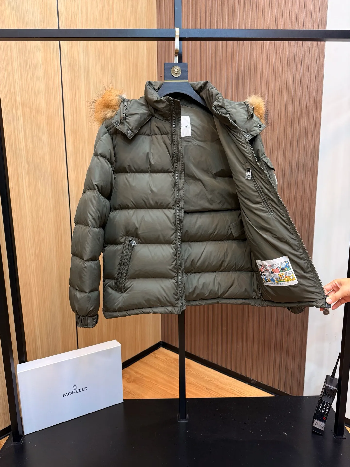 P1040 Moncler Mayaf short men's down jacket. The hood is removable. The fur collar is removable. Based on Maya, a removable fur collar is added. The Mayaf men's hooded down jacket is made of functional nylon fabric, and the hood is equipped with removable synthetic material trim.  The Mayaf short down jacket is a reinterpretation of the classic Moncler Maya style in an instantly recognizable silhouette, with a removable hood and adjustable hem. Made from functional fabric with removable synthetic trim on the hood. The sleeves are embellished with classic patch pockets, reflecting the brand's signature style. Details •Made from functional fabric •Technical fabric lining •Down-filled •Push-stud collar •Detachable hood with removable synthetic trim •Zip closure •Zip pockets •Patch pockets with press-stud •Adjustable elastic cuffs •Adjustable drawstring hem