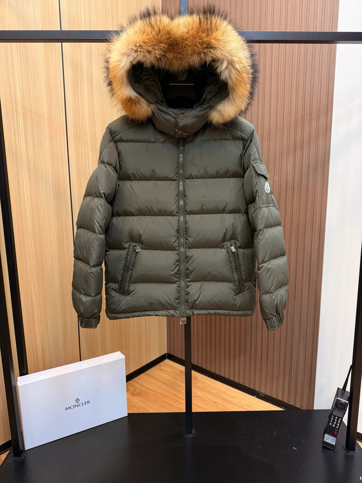 P1040 Moncler Mayaf short men's down jacket. The hood is removable. The fur collar is removable. Based on Maya, a removable fur collar is added. The Mayaf men's hooded down jacket is made of functional nylon fabric, and the hood is equipped with removable synthetic material trim.  The Mayaf short down jacket is a reinterpretation of the classic Moncler Maya style in an instantly recognizable silhouette, with a removable hood and adjustable hem. Made from functional fabric with removable synthetic trim on the hood. The sleeves are embellished with classic patch pockets, reflecting the brand's signature style. Details •Made from functional fabric •Technical fabric lining •Down-filled •Push-stud collar •Detachable hood with removable synthetic trim •Zip closure •Zip pockets •Patch pockets with press-stud •Adjustable elastic cuffs •Adjustable drawstring hem