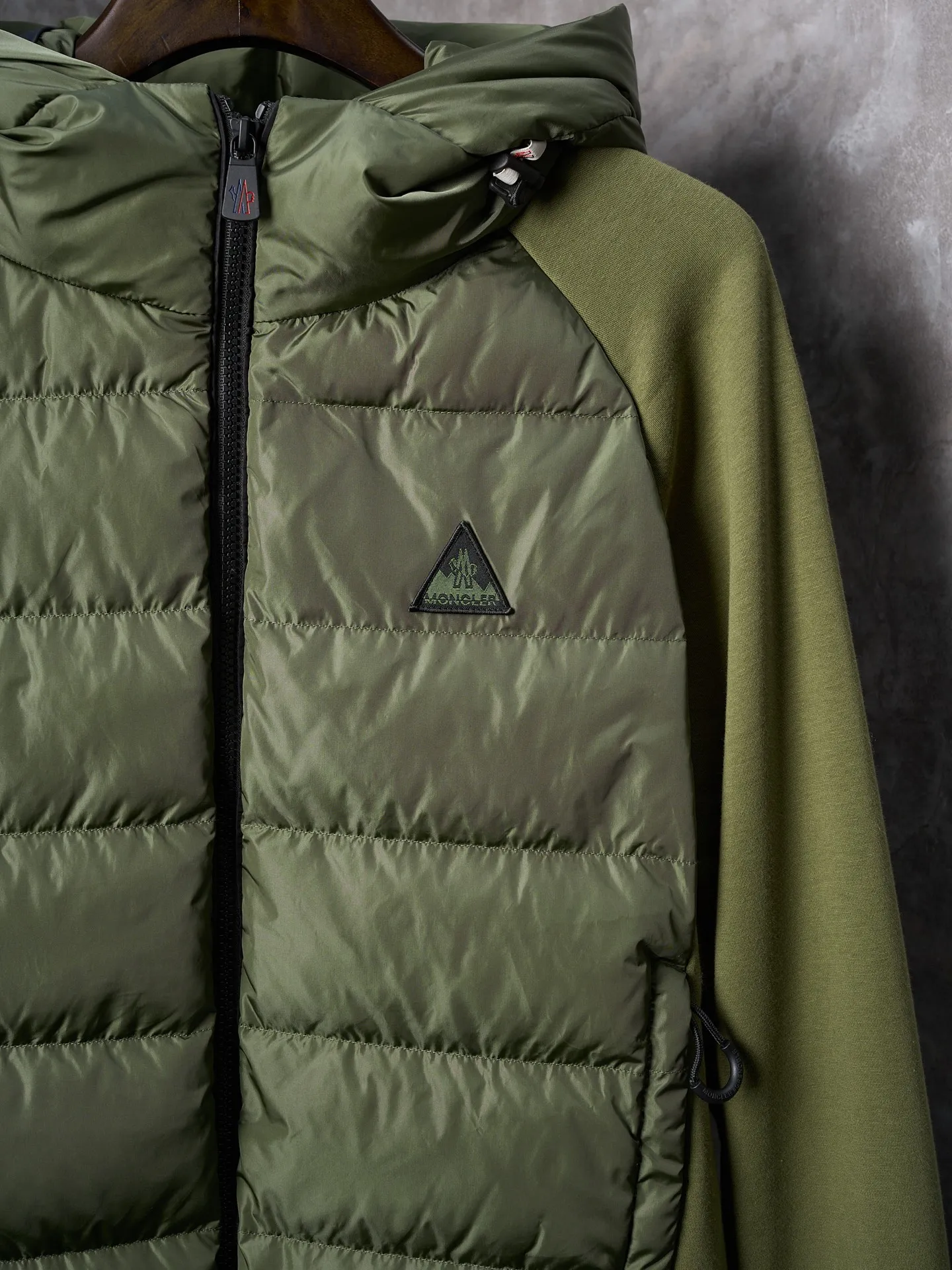 P780 Actual hanging auction] Moncler/Mongolian logo woven splicing down jacket [Ready stock] S M L XL custom matte lattice air shield velvet and 300D high-density calender coating. Use the new national standard 90 white duck down (welcome to test). Full of down content, full of warmth, light and fluffy. With the dark green of the overlapping mountains as the background color, all things are accumulating. The Monlcer triangle logo is embellished on the chest. The power aesthetics of the minimalist logo. The concentrated down filling in the front panel creates dynamic insulation for the core heat dissipation zone of the human body. The hooded down is a moving warm flow barrier for the head and neck, forming a thermal energy circulation system with the front panel. The elastic woven sleeves provide freedom of movement with a sense of compression, forming a relaxed and warm philosophy. Real high-end is to let function become the footnote of style. Computer-mechanical down filling gives priority to making liner paper patterns to determine the down filling area and determine the weight of down per square meter according to the original three-dimensional effect. Thus, the filling amount of each cut piece is calculated. The computerized down filling machine uses a digital weighing unit to achieve stable measurement. 3D three-dimensional quilting technology. With the help of the programming system of the CNC quilting machine, the down in different areas is accurately separated to ensure that the filling is evenly fixed after sewing to avoid agglomeration or shifting. The computer template machine runs the line. The computer template machine's line process shows extremely high neatness and smoothness. The craftsman accurately controls the size during the operation. Ensure that every line meets the design requirements. The lines of the entire template are smooth and unified, neat and beautiful. Triple locking and five-thread dense stitching technology. Main seam locking + diagonal reinforcement + raw edge wrapping. Triple structure forms a three-dimensional protective net at the edge of the fabric to avoid stitch breakage.