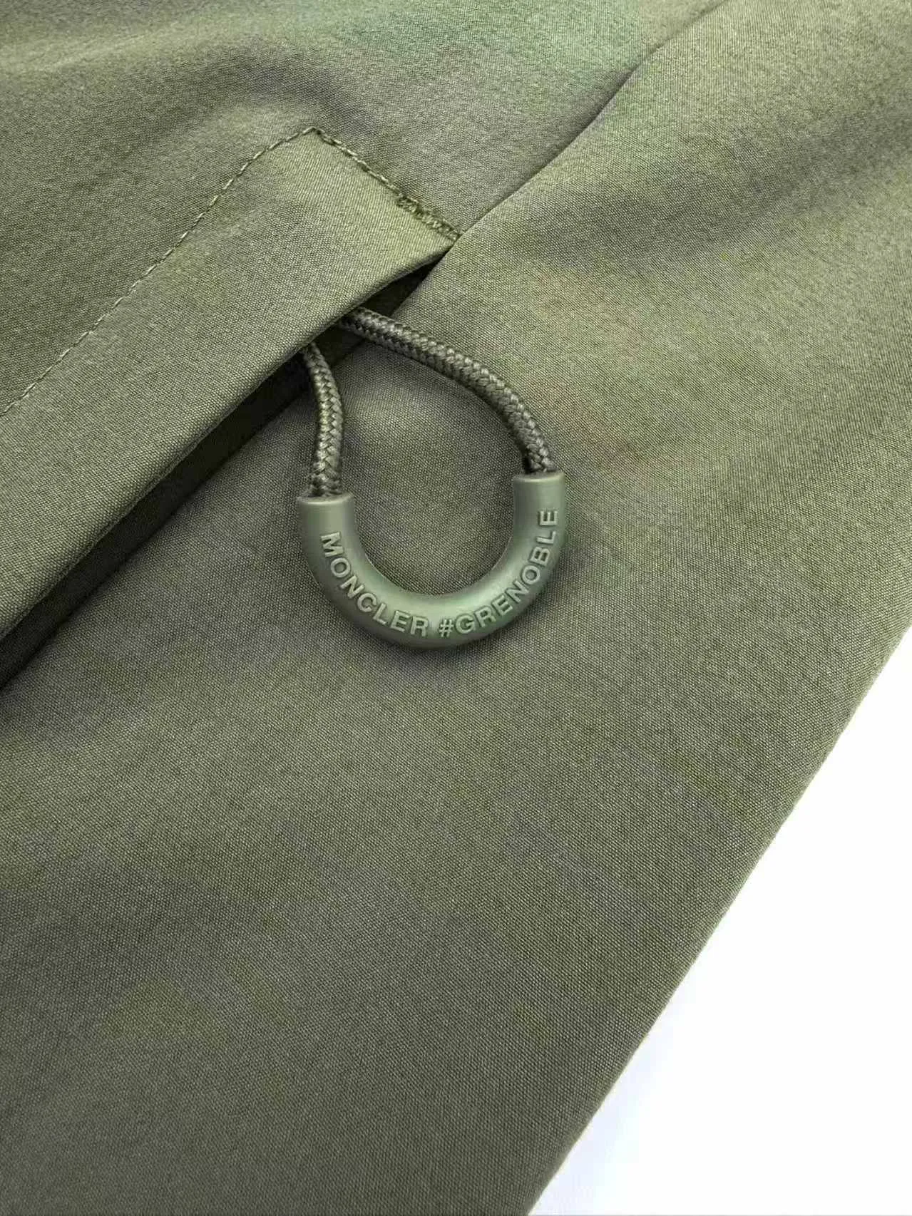 P560 Moncler Grenoble functional outdoor jacket Custom dyed double stretch mercerized poplin Custom dyed soft mesh pongee Excellent texture Comfortable and close to the skin Dark green inspired by plant texture The color is taken from sage leaves soaked in morning dew Precision narrative of functional pocket system Balance of function and aesthetics The iconic Moncler logo appears on the sleeves, fully recognizable The triangular logo of the same color is hidden in the fabric texture like a mark in the undercurrent of the deep sea, extremely invisible and yet obvious The detachable sleeve design allows for diversified outfits. You can switch styles at will. It is chic and free, showing nobility. It balances outdoor practicality and urban aesthetics and leads the fashion. Process 1: Adopt a three-in-one process. Prioritize and evenly coat the glue on the surface of the substrate that needs to be composited, and then dry and solidify it. Then laminate the substrate with the adhesive film and the non-woven fabric, then cool and solidify, and then composite it with the filter non-woven fabric. The workmanship is cumbersome and complex, time-consuming and labor-intensive. Process 2: Embossing composite technology uses computer scanning to ensure that the imprint size and shape are consistent with the original, and then uses special glue as an adhesive to combine and solidify to achieve complete dryness and the best bonding effect. Process 3: Use CNC laser burning and cutting. Based on the high-energy characteristics of the laser, the moving path of the laser beam is precisely controlled by the laser generator to achieve precise cutting of the shape of the piece. Process 4: Template machine bag opening. The preset template guides the position, shape and size of the bag opening. The accuracy ensures the quality of the bag opening effect. Process 5: Using infrared special machine buttoning, the position is more precise and strong. Accessories: Customized 1:1 Moncler snap button Customized 1:1 Moncler resin buckle Customized 1:1 Moncler logo seal Customized 1:1 Moncler logo armband Customized 1:1 Moncler zipper rope ring Customized 1:1 Moncler zipper pull Customized 1:1 Moncler trademark Version: Loose version Function: Detachable sleeve splicing Style can be switched at will Size: 1 2 3 4