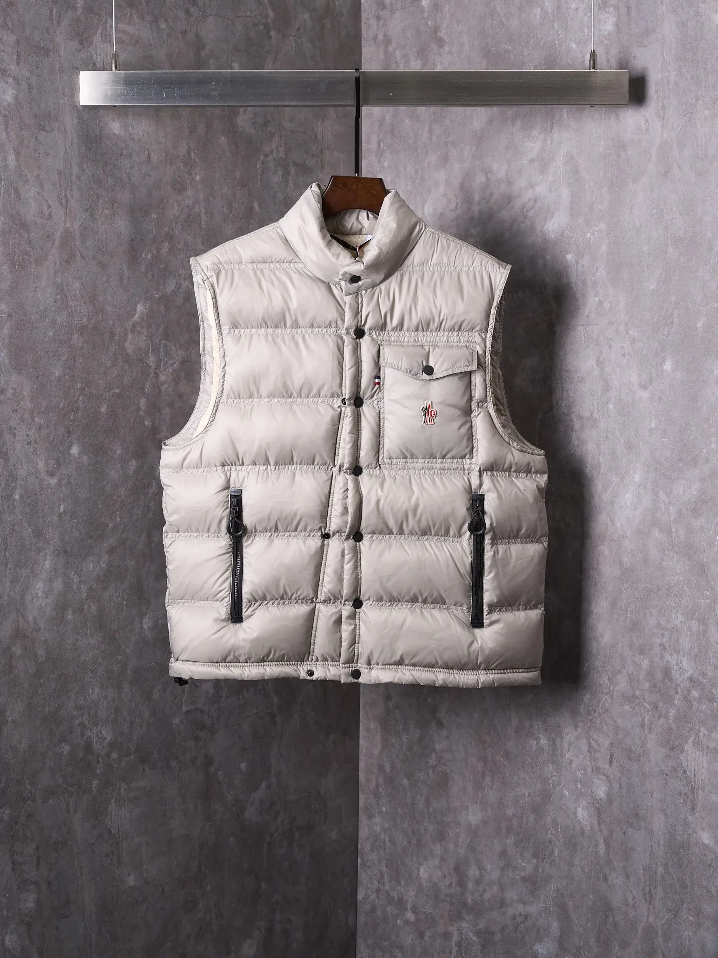 P680 Actual hanging auction] MONCLER/Mandow embroidered reflective logo stand-up collar down vest [Ready stock] 1 2 3 4 It is made of extremely fine nylon yarn and woven in a high-density way. The number of yarns per unit area is large, and the gaps between the yarns are very small, which can effectively block the penetration of cold wind. The fine weave keeps it lightweight and soft to the touch, physically restricting the lightweight down fibers from slipping through the gaps. Nylon fiber itself has good wear resistance and is not easy to snag, which significantly extends its service life and can easily cope with the needs of multiple scenarios.  The lining is made of high-density weaving of 100% polyester fiber, with a thickness of 0.08mm to avoid increasing the overall weight and making it smooth to wear. The high-density weaving structure forms a wind resistance layer to protect the thermal efficiency of the thermal layer from loss. It can withstand the expansion pressure of down and prevent deformation and damage after long-term use.  It uses 90 white duck down with a weight of 130g to ensure excellent thermal insulation performance. After strict screening and processing, the velvet is not easy to get drilled, ensuring durability.  Through the reflective cloth punching process, the logo is regularly arranged on the triangular reflective mark with dozens of small holes, which not only improves functionality but also enhances recognition and aesthetics.
