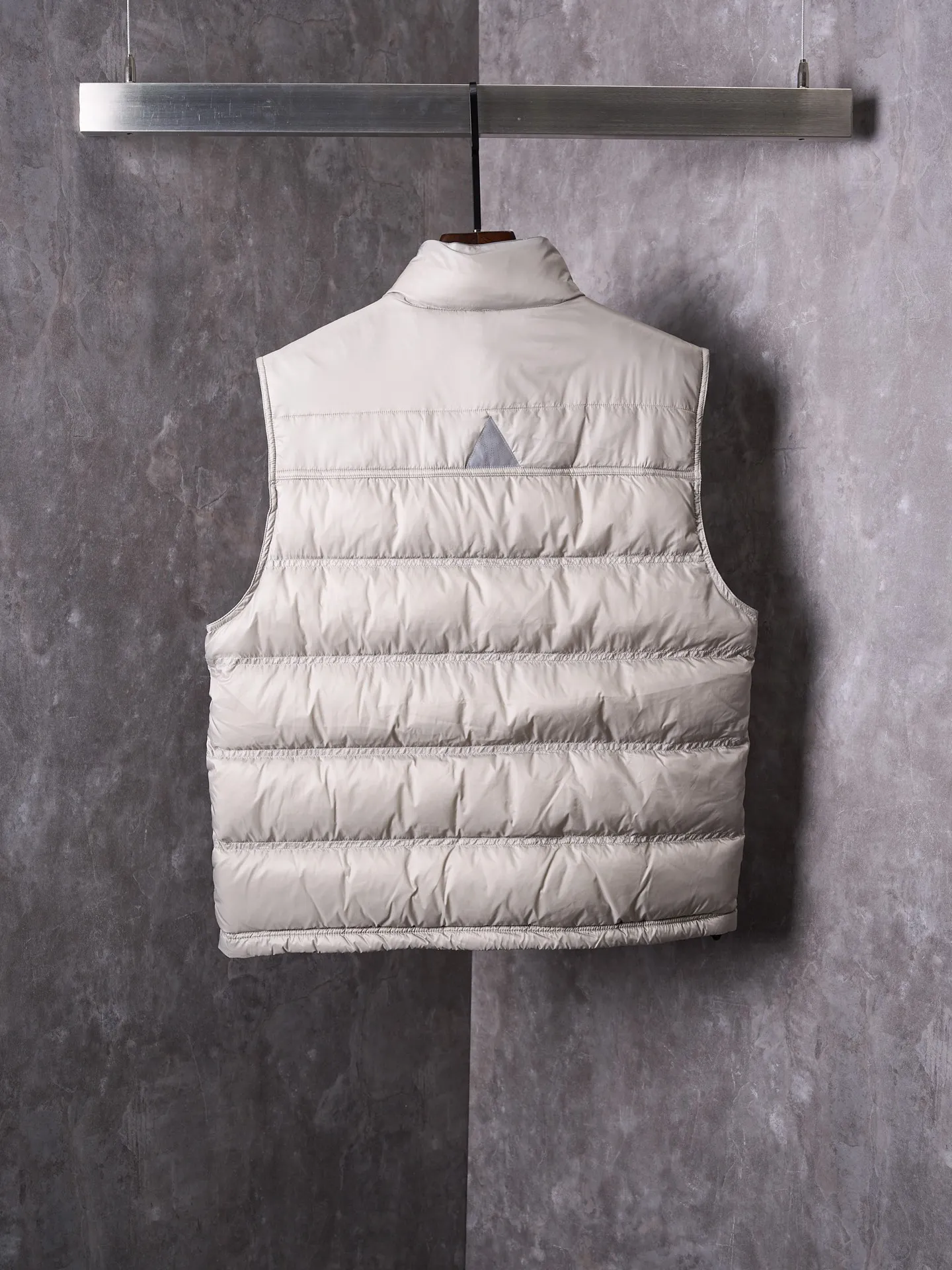 P680 Actual hanging auction] MONCLER/Mandow embroidered reflective logo stand-up collar down vest [Ready stock] 1 2 3 4 It is made of extremely fine nylon yarn and woven in a high-density way. The number of yarns per unit area is large, and the gaps between the yarns are very small, which can effectively block the penetration of cold wind. The fine weave keeps it lightweight and soft to the touch, physically restricting the lightweight down fibers from slipping through the gaps. Nylon fiber itself has good wear resistance and is not easy to snag, which significantly extends its service life and can easily cope with the needs of multiple scenarios.  The lining is made of high-density weaving of 100% polyester fiber, with a thickness of 0.08mm to avoid increasing the overall weight and making it smooth to wear. The high-density weaving structure forms a wind resistance layer to protect the thermal efficiency of the thermal layer from loss. It can withstand the expansion pressure of down and prevent deformation and damage after long-term use.  It uses 90 white duck down with a weight of 130g to ensure excellent thermal insulation performance. After strict screening and processing, the velvet is not easy to get drilled, ensuring durability.  Through the reflective cloth punching process, the logo is regularly arranged on the triangular reflective mark with dozens of small holes, which not only improves functionality but also enhances recognition and aesthetics.