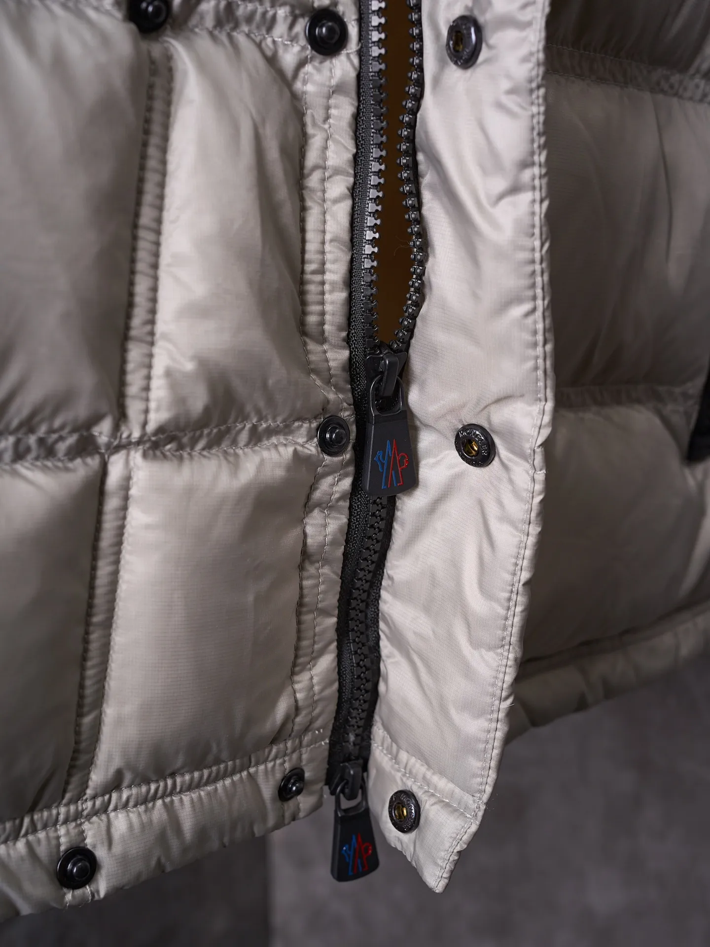 P680 Actual hanging auction] MONCLER/Mandow embroidered reflective logo stand-up collar down vest [Ready stock] 1 2 3 4 It is made of extremely fine nylon yarn and woven in a high-density way. The number of yarns per unit area is large, and the gaps between the yarns are very small, which can effectively block the penetration of cold wind. The fine weave keeps it lightweight and soft to the touch, physically restricting the lightweight down fibers from slipping through the gaps. Nylon fiber itself has good wear resistance and is not easy to snag, which significantly extends its service life and can easily cope with the needs of multiple scenarios.  The lining is made of high-density weaving of 100% polyester fiber, with a thickness of 0.08mm to avoid increasing the overall weight and making it smooth to wear. The high-density weaving structure forms a wind resistance layer to protect the thermal efficiency of the thermal layer from loss. It can withstand the expansion pressure of down and prevent deformation and damage after long-term use.  It uses 90 white duck down with a weight of 130g to ensure excellent thermal insulation performance. After strict screening and processing, the velvet is not easy to get drilled, ensuring durability.  Through the reflective cloth punching process, the logo is regularly arranged on the triangular reflective mark with dozens of small holes, which not only improves functionality but also enhances recognition and aesthetics.