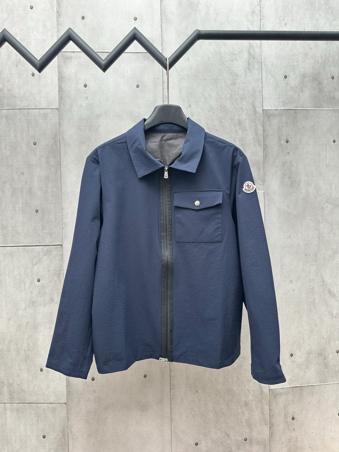 P440 MONCLER bubble wrinkle shirt jacket Fabric selection: Made of cotton blended woven fabric with 76% high cotton content + 24% polyester fiber. The high cotton content ensures that the fabric is soft, skin-friendly, and has good breathability. The addition of a small amount of polyester fiber balances the wrinkle resistance and elasticity of the overall fabric and greatly reduces its shrinkage. After preshrinking, dimensional changes during washing are negligible. The fusion of the two makes the fabric combine anti-wrinkle, quick-drying, easy care and other characteristics without losing the advantages of good wearing experience and strong breathability.  Bubble wrinkle technology: ground warp + bubble warp independent let-off. The bubble warp yarn feeding speed is about 20% higher than the ground warp yarn feeding speed. During weaving, the bubble warp is relaxed and accumulated, forming a naturally arched bubble unit. Through the alternating arrangement of yarns + floating length tissue changes, a clear grid frame is built between the bubble units, and finally the bubble three-dimensional effect and grid outline are locked through high-temperature heat setting.  Accessories: One-to-one customized zipper puller, one-to-one customized LOGO armband, one-to-one customized snap button SIZE: 1 2 3 4