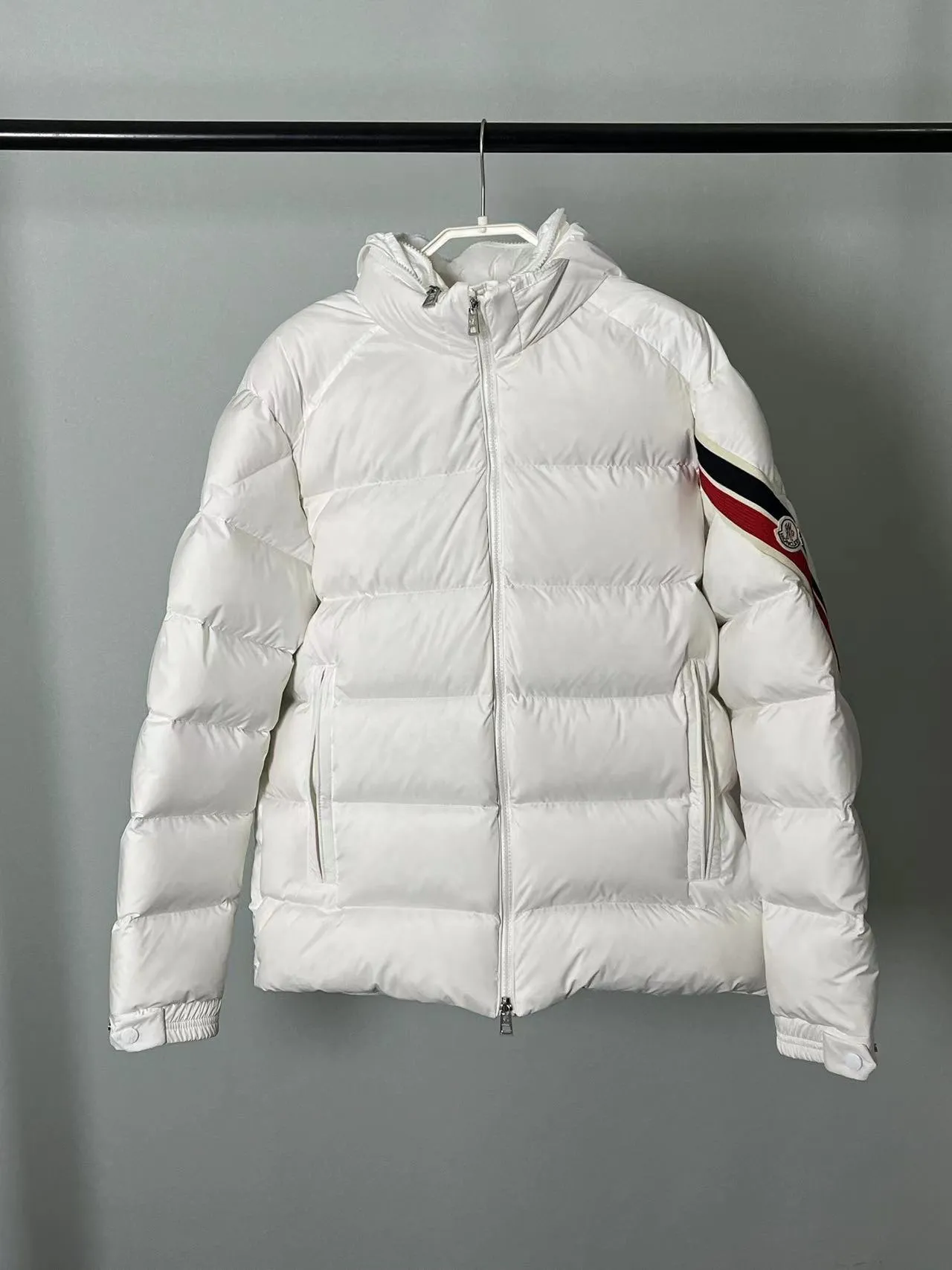 P920 🆕❤️2️⃣0️⃣2️⃣4️⃣Down⬆️Moncler Solayan men's tri-color trimmed short down jacket. Premium goose down filling. The finest, lightest and neatest fabric. Solayan men's short down jacket is decorated with seasonal iconic stripe details, blending sporty spirit and timeless style.  The Solayan down jacket is made of micro chic fabric and has a tough square shape design, highlighting Moncler's sporty spirit. This cropped down jacket features tricolor stripes on the sleeves, a seasonal take on the brand's signature. Comes with a practical pull-out hood. Details •Made from micro chic nylon fabric •Micro chic nylon lining •Down filled •Pull-out hood •Zip closure •Zip pockets •Adjustable cuffs •Elastic drawstring hem •Tri-color trim on sleeves Size: 1-5 Color: White Dark Brown Black