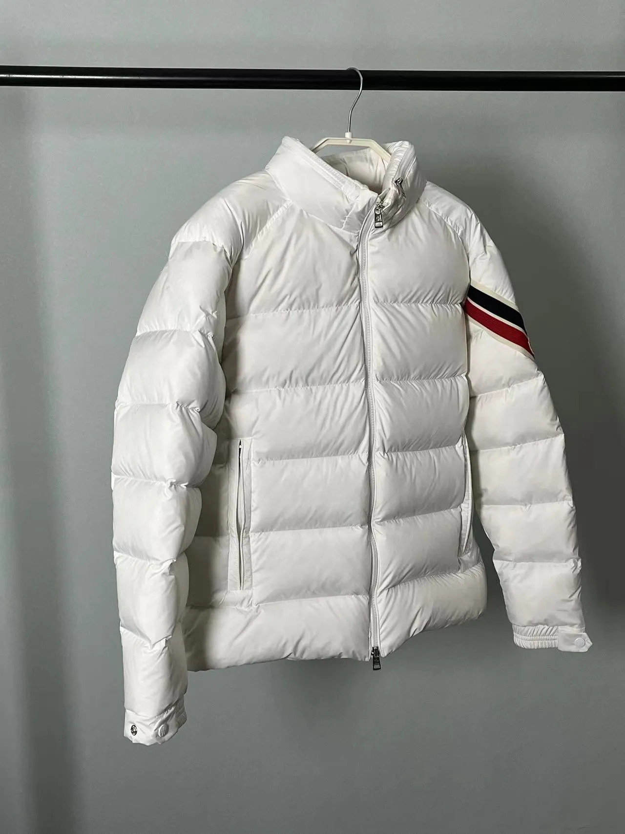 P920 🆕❤️2️⃣0️⃣2️⃣4️⃣Down⬆️Moncler Solayan men's tri-color trimmed short down jacket. Premium goose down filling. The finest, lightest and neatest fabric. Solayan men's short down jacket is decorated with seasonal iconic stripe details, blending sporty spirit and timeless style.  The Solayan down jacket is made of micro chic fabric and has a tough square shape design, highlighting Moncler's sporty spirit. This cropped down jacket features tricolor stripes on the sleeves, a seasonal take on the brand's signature. Comes with a practical pull-out hood. Details •Made from micro chic nylon fabric •Micro chic nylon lining •Down filled •Pull-out hood •Zip closure •Zip pockets •Adjustable cuffs •Elastic drawstring hem •Tri-color trim on sleeves Size: 1-5 Color: White Dark Brown Black