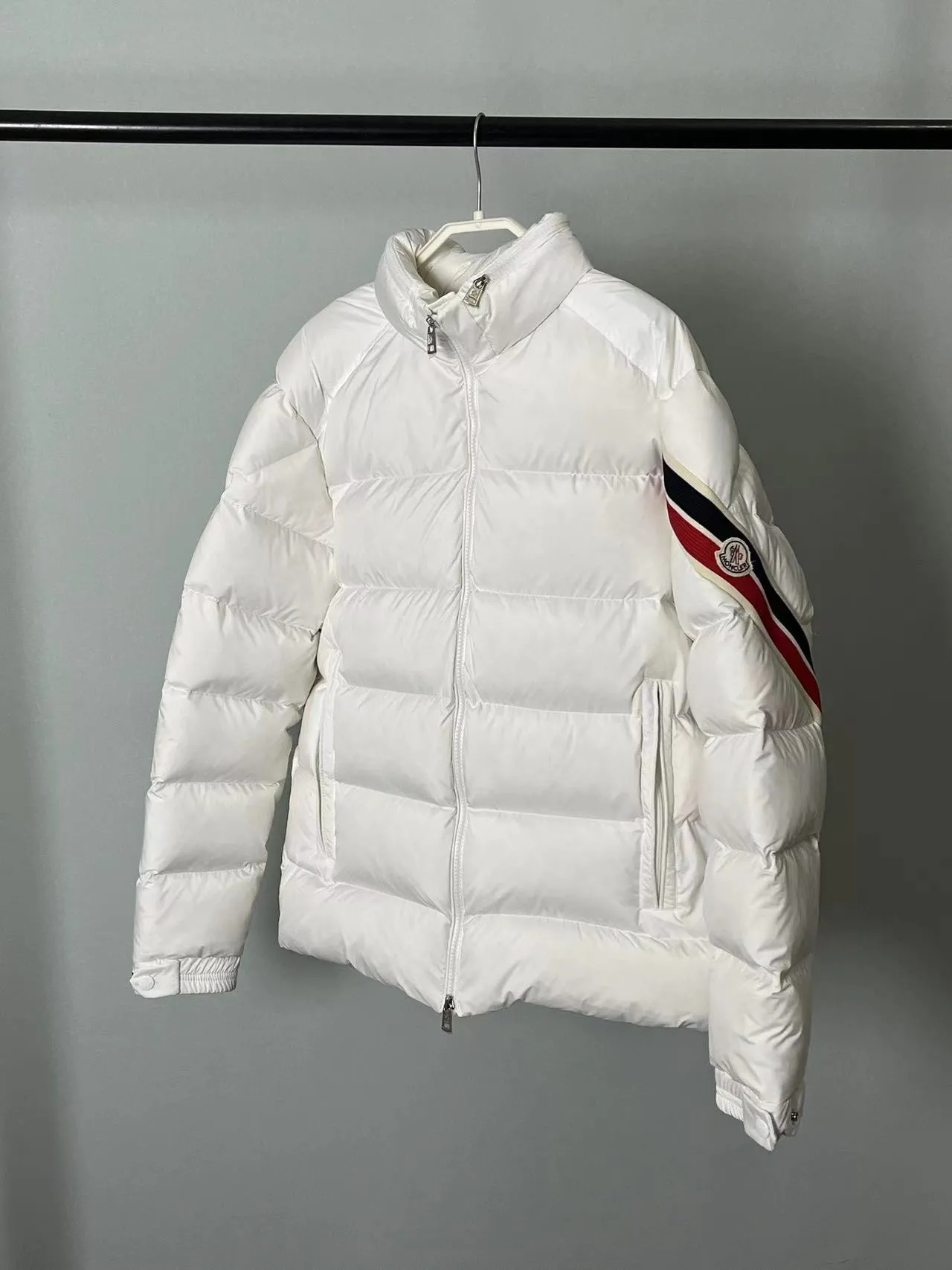 P920 🆕❤️2️⃣0️⃣2️⃣4️⃣Down⬆️Moncler Solayan men's tri-color trimmed short down jacket. Premium goose down filling. The finest, lightest and neatest fabric. Solayan men's short down jacket is decorated with seasonal iconic stripe details, blending sporty spirit and timeless style.  The Solayan down jacket is made of micro chic fabric and has a tough square shape design, highlighting Moncler's sporty spirit. This cropped down jacket features tricolor stripes on the sleeves, a seasonal take on the brand's signature. Comes with a practical pull-out hood. Details •Made from micro chic nylon fabric •Micro chic nylon lining •Down filled •Pull-out hood •Zip closure •Zip pockets •Adjustable cuffs •Elastic drawstring hem •Tri-color trim on sleeves Size: 1-5 Color: White Dark Brown Black