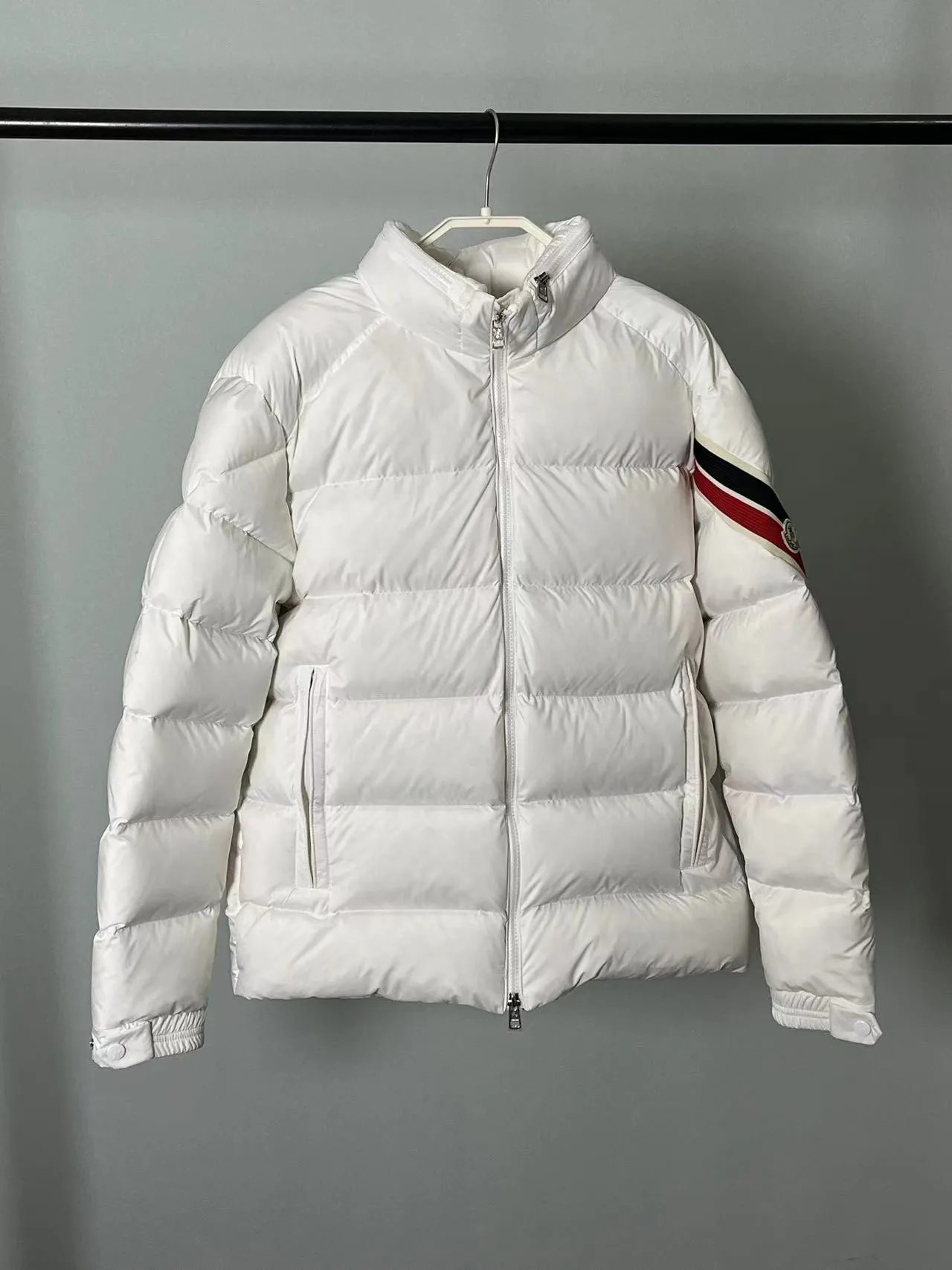 P920 🆕❤️2️⃣0️⃣2️⃣4️⃣Down⬆️Moncler Solayan men's tri-color trimmed short down jacket. Premium goose down filling. The finest, lightest and neatest fabric. Solayan men's short down jacket is decorated with seasonal iconic stripe details, blending sporty spirit and timeless style.  The Solayan down jacket is made of micro chic fabric and has a tough square shape design, highlighting Moncler's sporty spirit. This cropped down jacket features tricolor stripes on the sleeves, a seasonal take on the brand's signature. Comes with a practical pull-out hood. Details •Made from micro chic nylon fabric •Micro chic nylon lining •Down filled •Pull-out hood •Zip closure •Zip pockets •Adjustable cuffs •Elastic drawstring hem •Tri-color trim on sleeves Size: 1-5 Color: White Dark Brown Black