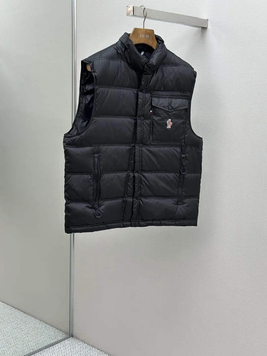 P680 MONCLER down vest with reflective markings Fabric selection: Made of ultra-fine nylon yarn woven in a high-density manner. The number of yarns per unit area is large, and the gaps between the yarns are very small, which can effectively block the penetration of cold wind. The fine weave keeps it lightweight and soft to the touch, physically restricting the lightweight down fibers from slipping through the gaps. Nylon fiber itself has good wear resistance and is not easy to snag, which significantly extends its service life and can easily cope with the needs of multiple scenarios.  Lining selection: The lining is made of 100% polyester fiber high-density weaving. The thickness of 0.08mm avoids increasing the overall weight and makes it smooth to wear. The high-density weaving structure forms a wind resistance layer to protect the thermal efficiency of the thermal insulation layer from loss. At the same time, it can withstand the expansion pressure of down and prevent deformation and damage after long-term use.  High-quality filling: 90 white duck down is selected, with a weight of 130g, ensuring excellent thermal insulation performance. After strict screening and processing, the velvet is not easy to get drilled, ensuring durability.  Process: Through the reflective cloth punching process, the logo is regularly arranged on the triangular reflective mark with dozens of small holes, which not only improves the functionality, but also strengthens the recognition and aesthetics.   Accessories: Customized snap buttons, customized zipper pullers, customized badges, customized elastic buckles, etc. SIZE: 1 2 3 4