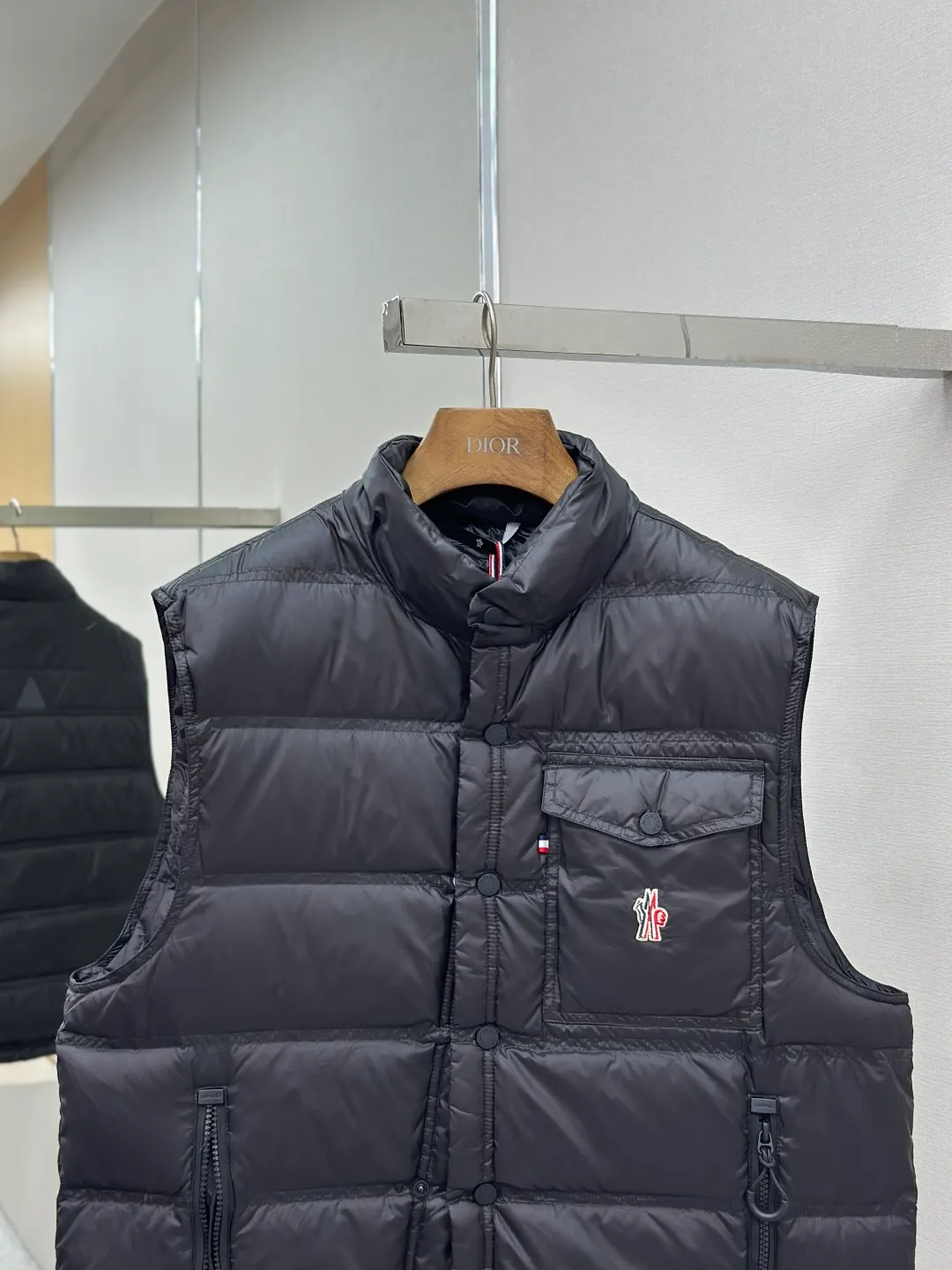 P680 MONCLER down vest with reflective markings Fabric selection: Made of ultra-fine nylon yarn woven in a high-density manner. The number of yarns per unit area is large, and the gaps between the yarns are very small, which can effectively block the penetration of cold wind. The fine weave keeps it lightweight and soft to the touch, physically restricting the lightweight down fibers from slipping through the gaps. Nylon fiber itself has good wear resistance and is not easy to snag, which significantly extends its service life and can easily cope with the needs of multiple scenarios.  Lining selection: The lining is made of 100% polyester fiber high-density weaving. The thickness of 0.08mm avoids increasing the overall weight and makes it smooth to wear. The high-density weaving structure forms a wind resistance layer to protect the thermal efficiency of the thermal insulation layer from loss. At the same time, it can withstand the expansion pressure of down and prevent deformation and damage after long-term use.  High-quality filling: 90 white duck down is selected, with a weight of 130g, ensuring excellent thermal insulation performance. After strict screening and processing, the velvet is not easy to get drilled, ensuring durability.  Process: Through the reflective cloth punching process, the logo is regularly arranged on the triangular reflective mark with dozens of small holes, which not only improves the functionality, but also strengthens the recognition and aesthetics.   Accessories: Customized snap buttons, customized zipper pullers, customized badges, customized elastic buckles, etc. SIZE: 1 2 3 4