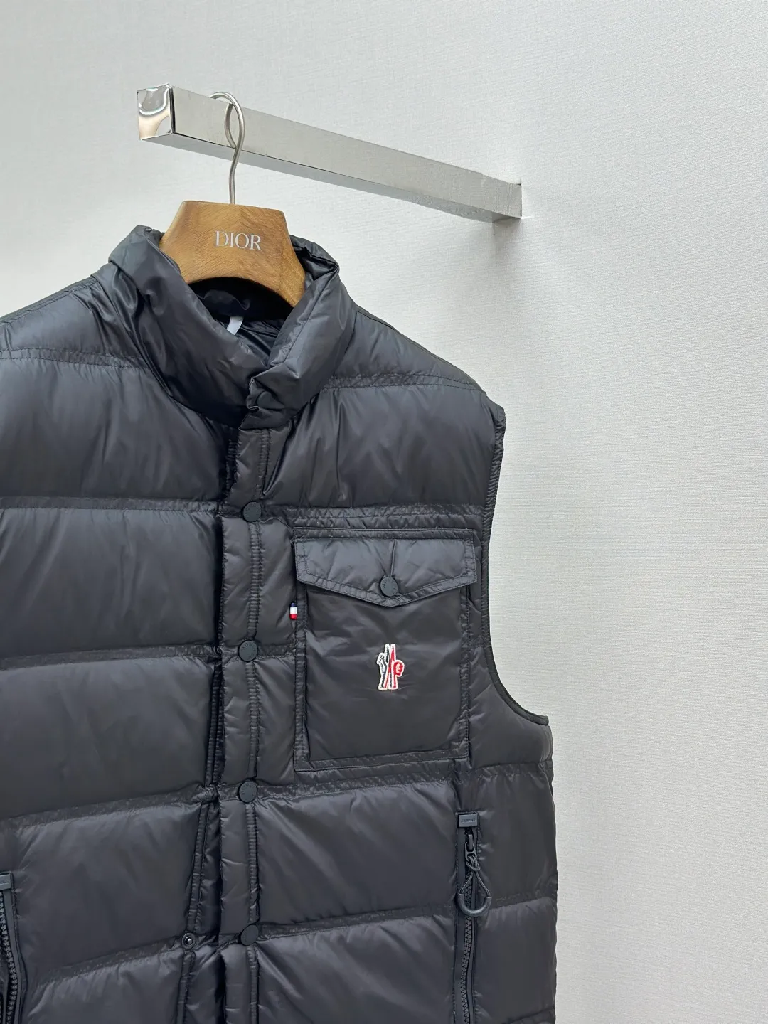 P680 MONCLER down vest with reflective markings Fabric selection: Made of ultra-fine nylon yarn woven in a high-density manner. The number of yarns per unit area is large, and the gaps between the yarns are very small, which can effectively block the penetration of cold wind. The fine weave keeps it lightweight and soft to the touch, physically restricting the lightweight down fibers from slipping through the gaps. Nylon fiber itself has good wear resistance and is not easy to snag, which significantly extends its service life and can easily cope with the needs of multiple scenarios.  Lining selection: The lining is made of 100% polyester fiber high-density weaving. The thickness of 0.08mm avoids increasing the overall weight and makes it smooth to wear. The high-density weaving structure forms a wind resistance layer to protect the thermal efficiency of the thermal insulation layer from loss. At the same time, it can withstand the expansion pressure of down and prevent deformation and damage after long-term use.  High-quality filling: 90 white duck down is selected, with a weight of 130g, ensuring excellent thermal insulation performance. After strict screening and processing, the velvet is not easy to get drilled, ensuring durability.  Process: Through the reflective cloth punching process, the logo is regularly arranged on the triangular reflective mark with dozens of small holes, which not only improves the functionality, but also strengthens the recognition and aesthetics.   Accessories: Customized snap buttons, customized zipper pullers, customized badges, customized elastic buckles, etc. SIZE: 1 2 3 4