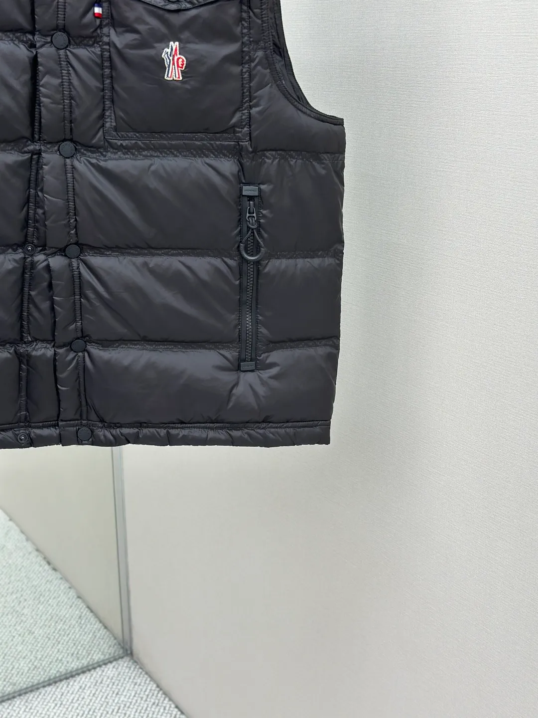 P680 MONCLER down vest with reflective markings Fabric selection: Made of ultra-fine nylon yarn woven in a high-density manner. The number of yarns per unit area is large, and the gaps between the yarns are very small, which can effectively block the penetration of cold wind. The fine weave keeps it lightweight and soft to the touch, physically restricting the lightweight down fibers from slipping through the gaps. Nylon fiber itself has good wear resistance and is not easy to snag, which significantly extends its service life and can easily cope with the needs of multiple scenarios.  Lining selection: The lining is made of 100% polyester fiber high-density weaving. The thickness of 0.08mm avoids increasing the overall weight and makes it smooth to wear. The high-density weaving structure forms a wind resistance layer to protect the thermal efficiency of the thermal insulation layer from loss. At the same time, it can withstand the expansion pressure of down and prevent deformation and damage after long-term use.  High-quality filling: 90 white duck down is selected, with a weight of 130g, ensuring excellent thermal insulation performance. After strict screening and processing, the velvet is not easy to get drilled, ensuring durability.  Process: Through the reflective cloth punching process, the logo is regularly arranged on the triangular reflective mark with dozens of small holes, which not only improves the functionality, but also strengthens the recognition and aesthetics.   Accessories: Customized snap buttons, customized zipper pullers, customized badges, customized elastic buckles, etc. SIZE: 1 2 3 4