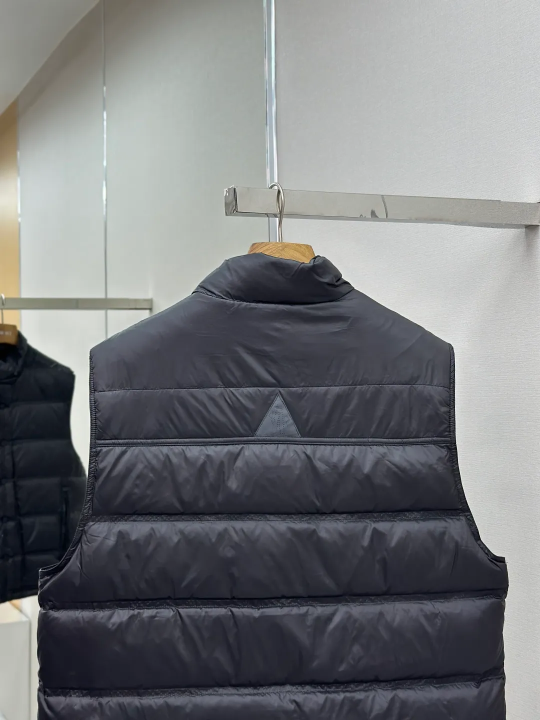 P680 MONCLER down vest with reflective markings Fabric selection: Made of ultra-fine nylon yarn woven in a high-density manner. The number of yarns per unit area is large, and the gaps between the yarns are very small, which can effectively block the penetration of cold wind. The fine weave keeps it lightweight and soft to the touch, physically restricting the lightweight down fibers from slipping through the gaps. Nylon fiber itself has good wear resistance and is not easy to snag, which significantly extends its service life and can easily cope with the needs of multiple scenarios.  Lining selection: The lining is made of 100% polyester fiber high-density weaving. The thickness of 0.08mm avoids increasing the overall weight and makes it smooth to wear. The high-density weaving structure forms a wind resistance layer to protect the thermal efficiency of the thermal insulation layer from loss. At the same time, it can withstand the expansion pressure of down and prevent deformation and damage after long-term use.  High-quality filling: 90 white duck down is selected, with a weight of 130g, ensuring excellent thermal insulation performance. After strict screening and processing, the velvet is not easy to get drilled, ensuring durability.  Process: Through the reflective cloth punching process, the logo is regularly arranged on the triangular reflective mark with dozens of small holes, which not only improves the functionality, but also strengthens the recognition and aesthetics.   Accessories: Customized snap buttons, customized zipper pullers, customized badges, customized elastic buckles, etc. SIZE: 1 2 3 4