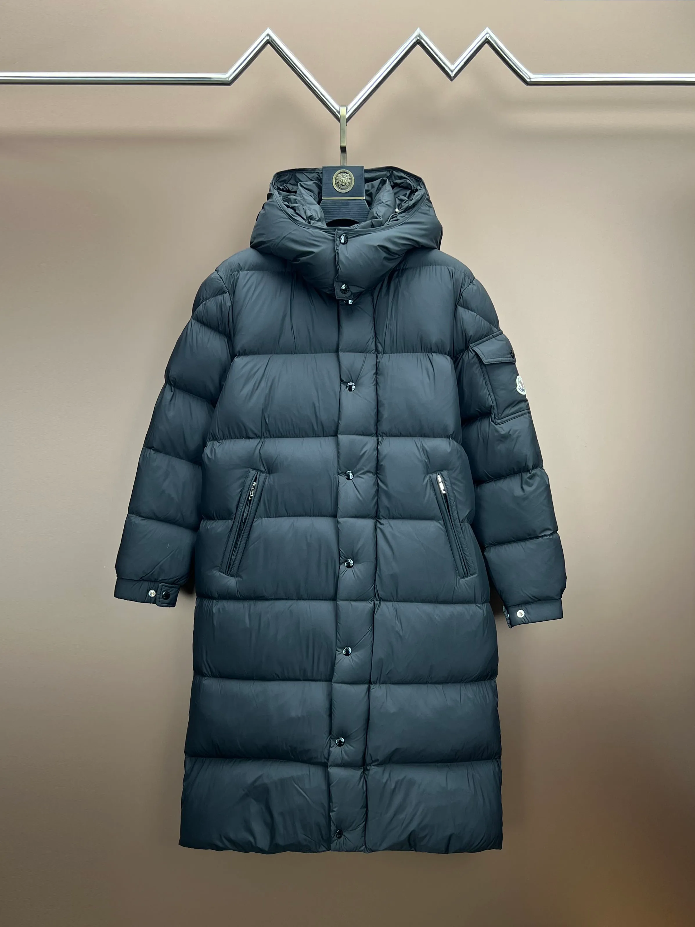 P920 Moncler Hanoverian line (matte matte) long men's. 850+ fill power, this Hanoverian men's long down combines Moncler's classic aesthetics, excellent performance and protective features. Hanoverian long down is made of longue saison fabric and is designed with practical details to provide both warmth and protection. As a Moncler classic, this model features a detachable hood and a front zipper placket that covers the windshield, significantly improving its protective performance. Details Made of longue saison fabric Longue saison lining Filled with down Removable hood Zipper and snap fastening Zippered pockets Patch pockets on sleeves Adjustable cuffs Drawstring hem Size: 0-4 (couple size)