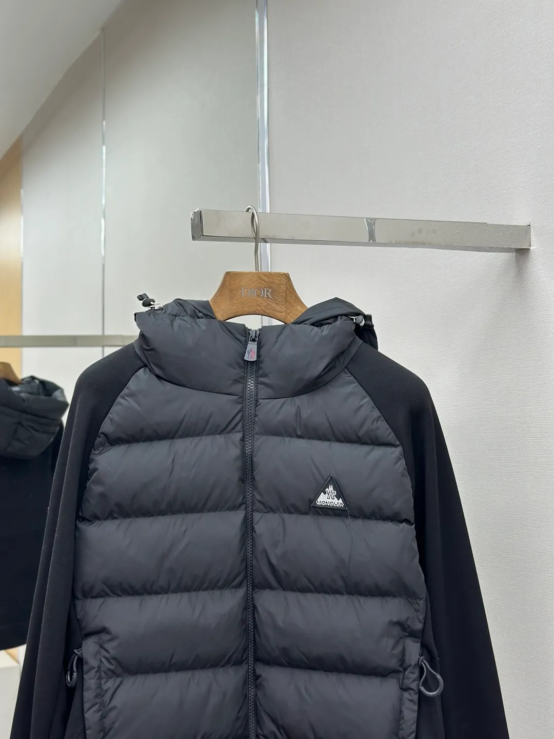 P810 Moncler logo woven splicing down jacket, customized matte crystal lattice air shield velvet and 300D high-density calendered coating, using the new national standard 90 white duck down (welcome to test), full of down, full of warmth, light and fluffy, with the dark green of the overlapping mountains as the background color, all things accumulating, creating its own scenery in silence The Monlcer triangle logo is embellished on the chest, the power aesthetics of the minimalist logo The concentrated down filling in the front area creates dynamic insulation for the core heat dissipation zone of the human body. The hooded down is a moving warm flow barrier for the head and neck, forming a thermal energy circulation system with the front area. The elastic woven sleeves provide freedom of movement with a sense of compression, forming a relaxed and warm philosophy. The real high-end is to let function become the footnote of style. Process 1: Computer mechanical down filling. Prioritize the liner pattern by making a pattern to determine the down filling area and determine the weight of down per square meter according to the original three-dimensional effect. Thus, the amount of down filling for each cut piece is calculated. The computer down filling machine uses a digital weighing unit to achieve stable measurement. Process 2: 3D three-dimensional quilting technology. With the programming system of the CNC quilting machine, the down in different areas is accurately separated to ensure that the filling is evenly fixed after sewing and avoid agglomeration or displacement. Process 3: Computer template machine line running process. The computer template machine line line process shows extremely high neatness and smoothness. The craftsman's precise control of the size during the operation ensures that each line meets the design requirements. The lines of the entire template are smooth and unified, neat and beautiful. Process 4: Triple locking five-thread dense stitching process. Main seam locking + diagonal reinforcement + raw edge wrapping. Triple structure. Forming a three-dimensional protective net at the edge of the fabric to avoid stitch breakage. Paving materials: Customized Moncler zippers. Customized Moncler rope loops. Customized Moncler logo. Customized Moncler eyelets. Customized Moncler trademark. Size: S M L XL
