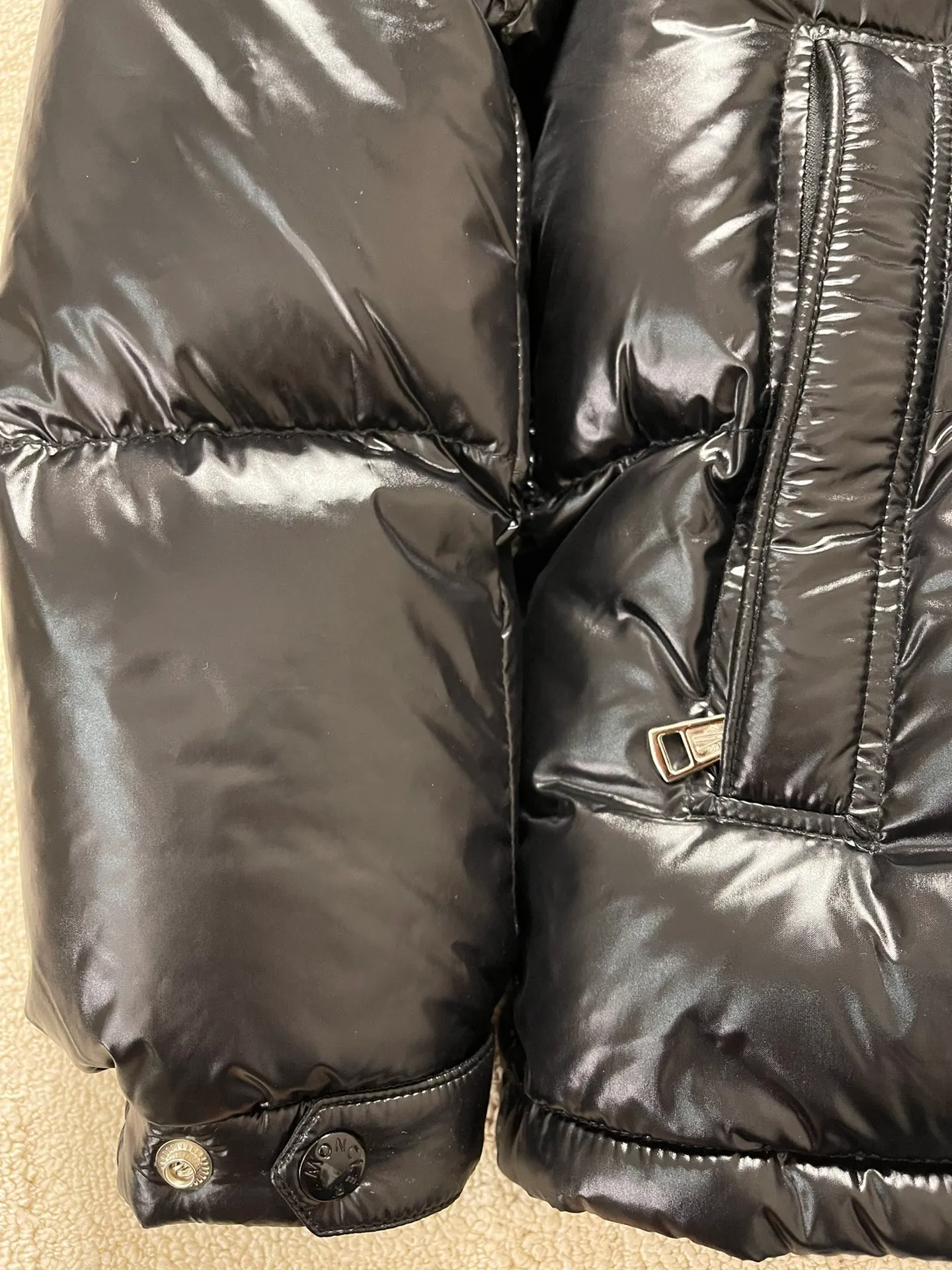 Flat detail P1180 Moncler Montbeliard glossy down jacket The Montbeliard down jacket is made of shiny patented nylon and features highly recognizable rectangular quilting. Featuring a hooded design and signature patch pocket at chest.  Fabric: 100% nylon Filling content: 90% white goose down 250-300g Craftsmanship: Made of nylon laqué fabric Nylon laque lining Filled with down, detachable and adjustable hood with drawstring closure Built-in flap with webbing, black pocket details at the lower end Zipper closure Collar with snap buttons Zipper pockets Patch pockets with snap buttons Adjustable cuffs Adjustable elastic drawstring hem.  Size: 1 2 3 4 5 0548000